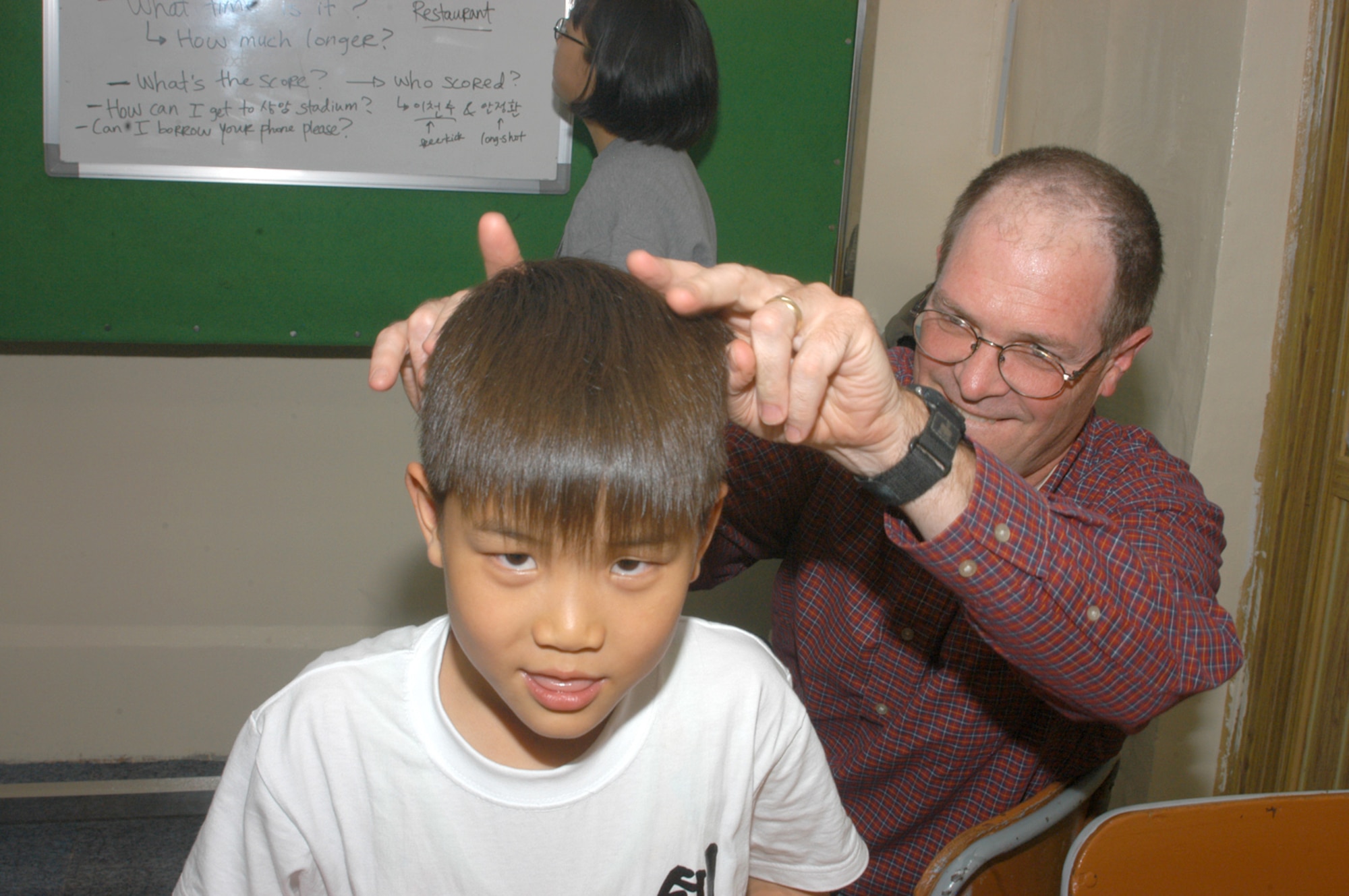 KUNSAN AIR BASE, Republic of Korea -- Lt. Col. John Allen (right), together with a Korean english-class student, has a little fun in front of the Wolf Pack Warrior during class. (Air Force photo by Staff Sgt. Becky Nelson)                                