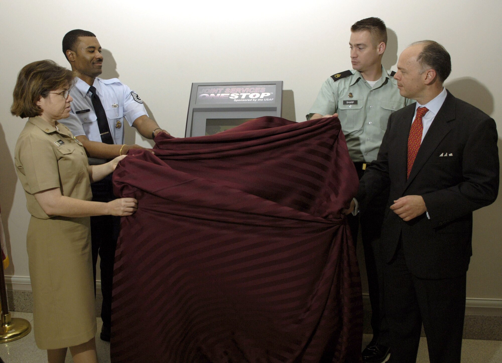 (From left) Navy Chief Petty Officer Jana Perez, Tech. Sgt. Timothy Gerald and Army Staff Sgt. Lonny Sharp unveil the new Joint Services OneStop Kiosk at the Pentagon on Thursday, June 29, with John Vonglis, principal deputy assistant secretary of the Air Force for financial management. (U.S. Air Force photo/Tech. Sgt. Cohen A. Young)