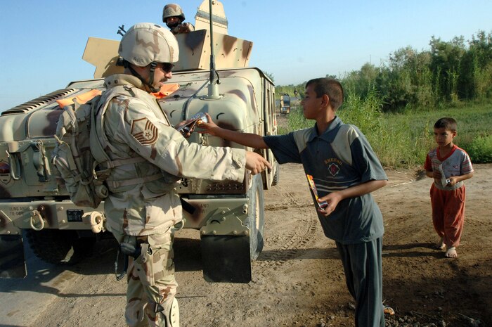 Master Sgt. Christopher Nolan gives out toys to children before the start of an Army exercise in Baghdad, Iraq, on Saturday, June 24. Sergeant Nolan is a combat videographer with the 1st Combat Camera Squadron at Charleston Air Force Base, S.C. (U.S. Army photo/Staff Sgt. Kevin L. Moses Sr.) 
