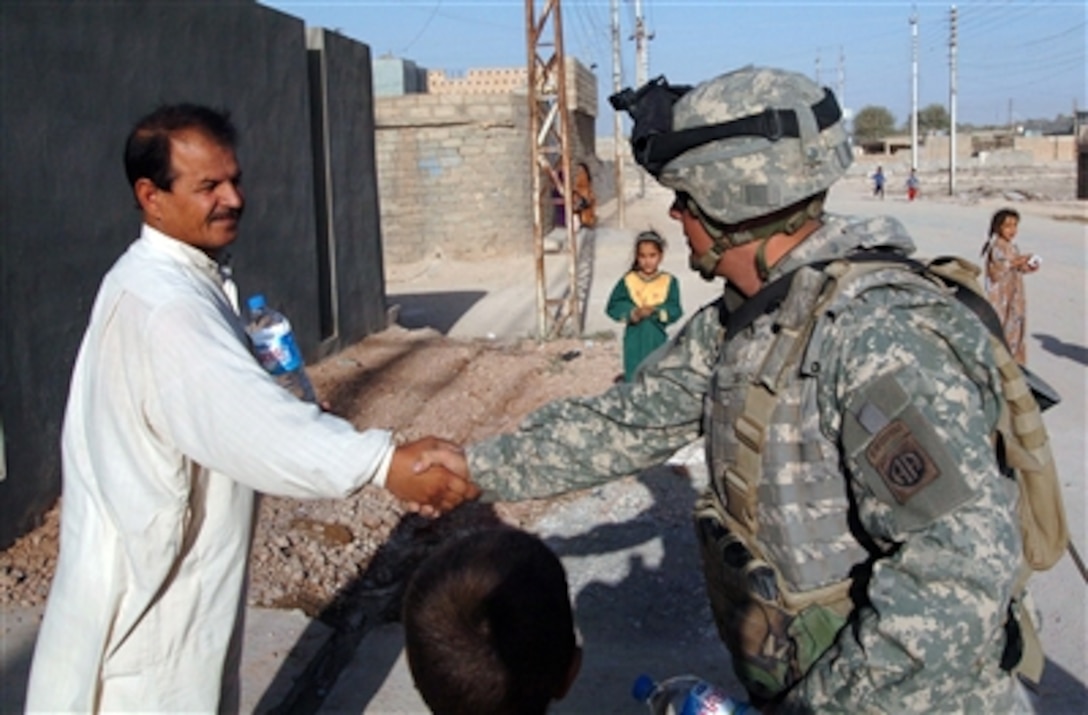 U.S. Army Spc. Justin Brown of the 325th Airborne Infantry Regiment, 82nd Airborne Division, Delta Company, 2nd Battalion, Fort Bragg, N.C., shakes hands with an Iraqi man after giving him food and water in Tal Afar, Iraq, Sept. 23, 2005.