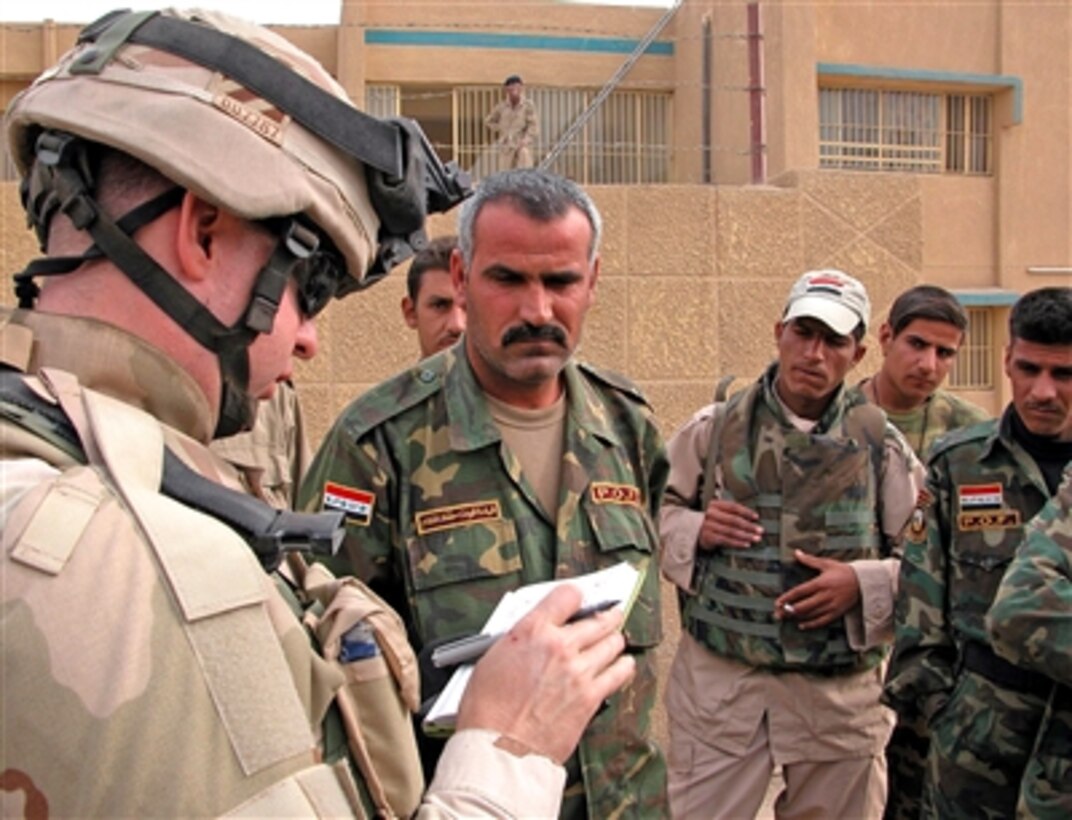 U.S. Army Capt. David Underhill (left) speaks with members of the Iraqi security forces outside a school in East Baghdad. The school will be a polling station for the Dec. 15 election and Underhill and his unit - 1st Battalion, 9th Field Artillery - are providing assistance. 