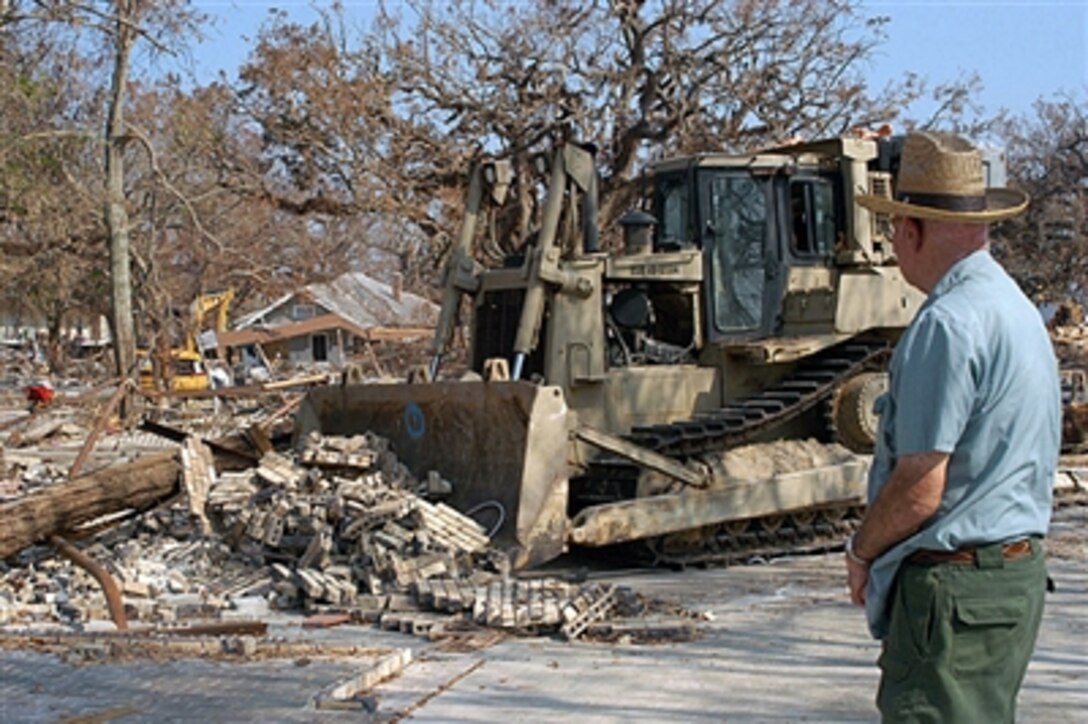 A resident of Biloxi, Miss., whose shore-side home was leveled by Hurricane Katrina, watches as a U.S. Navy sailor from Beachmaster Unit 2 clears rubble from his land with a bulldozer on Sept. 15, 2005. Department of Defense units are mobilized as part of Joint Task Force Katrina to support the Federal Emergency Management Agency's disaster-relief efforts in the Gulf Coast areas devastated by Hurricane Katrina.