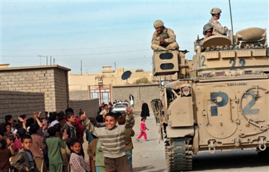 Iraqi children gather around a Bradley tank, from 3rd Armored Cavalry Regiment, Tiger Squadron, Predator Troop, as Iraqi Army soldiers distribute supplies to the school in Khan as Sur, Iraq, Nov. 25, 2005. Iraqi Army Security Forces with assistance from the 3rd Armored Cavalry Regiment are providing security for the region of Sinjar.  