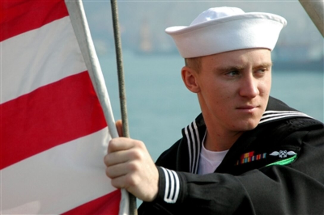 U.S. Navy Airman Michael Piersall prepares to raise the First Navy Jack on the flight deck of the USS Kitty Hawk after dropping anchor in Hong Kong, Nov. 24, 2005. Currently in port, the Kitty Hawk demonstrates power projection and sea control as the U.S. Navy's only forward-deployed aircraft carrier, operating from Yokosuka, Japan.