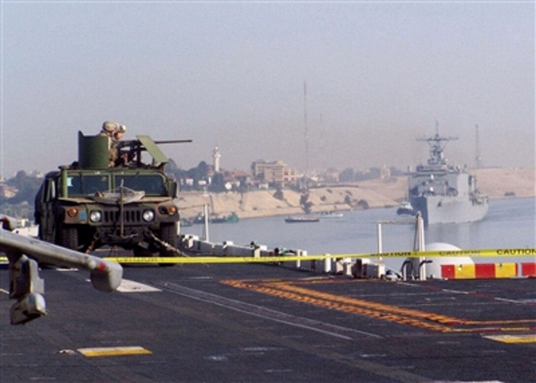 With the amphibious assault ship USS Carter Hall trailing closely behind, infantrymen provide security with a machine gun-equipped Humvee on the flight deck of the USS Nassau as the ship transits the Suez Canal, Nov. 26, 2005. In recent years the Suez Canal has earned the unofficial moniker as "the gateway to combat," reflecting the ongoing security and stability operations in the Central Command theater.