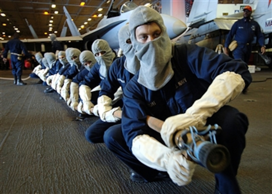 Sailors assigned to Repair Locker One Bravo stand ready to battle a simulated fire while manning a two-inch fire hose during a general quarters drill in the hangar bay of the nuclear-powered aircraft carrier USS Enterprise, Oct. 31, 2005. 
