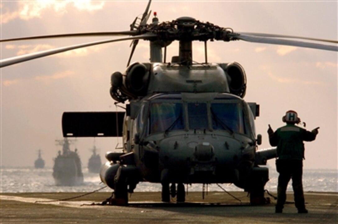 A sailor signals to the pilot of an HH-60H Seahawk helicopter, assigned to the "Chargers" of Helicopter Anti-Submarine Squadron 14, during start-up procedures aboard the USS Kitty Hawk, Nov. 12, 2005, in the Tsugaru Strait. The ship is participating in a bilateral Annual Exercise 2005 with the Japan Maritime Self-Defense Force. 
