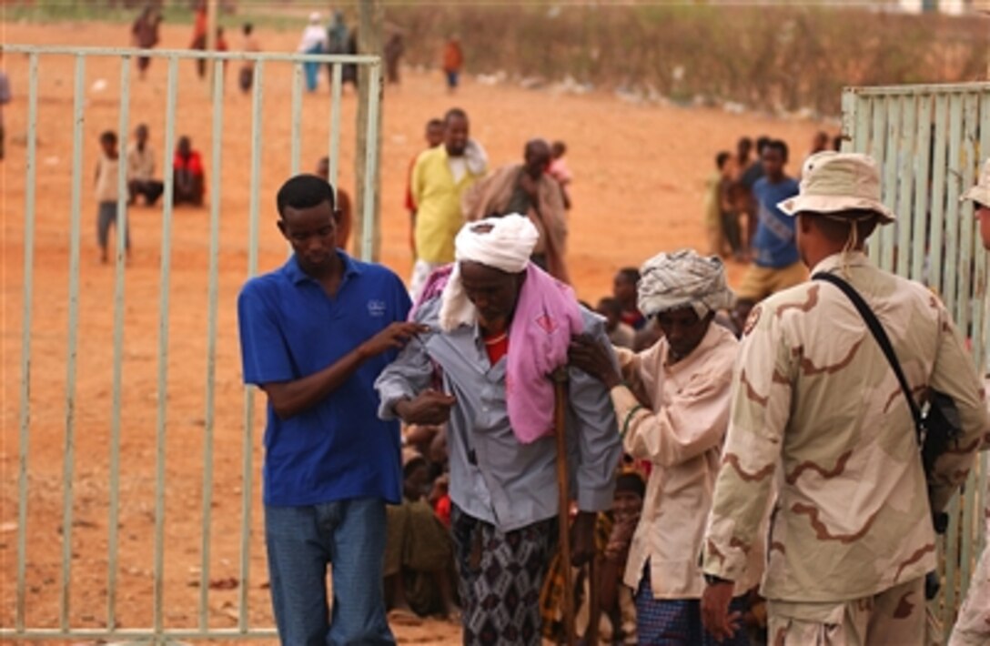 An elderly man receives help walking through a gate to the compound  in Gode, Ethiopia, Nov. 9, 2005.  Military medical personnel from Combined Joint Task Force-Horn of Africa participate d in a three-day medical civic action program called Honest Eclipse, which provided aid to more than 2,000 Ethiopians.