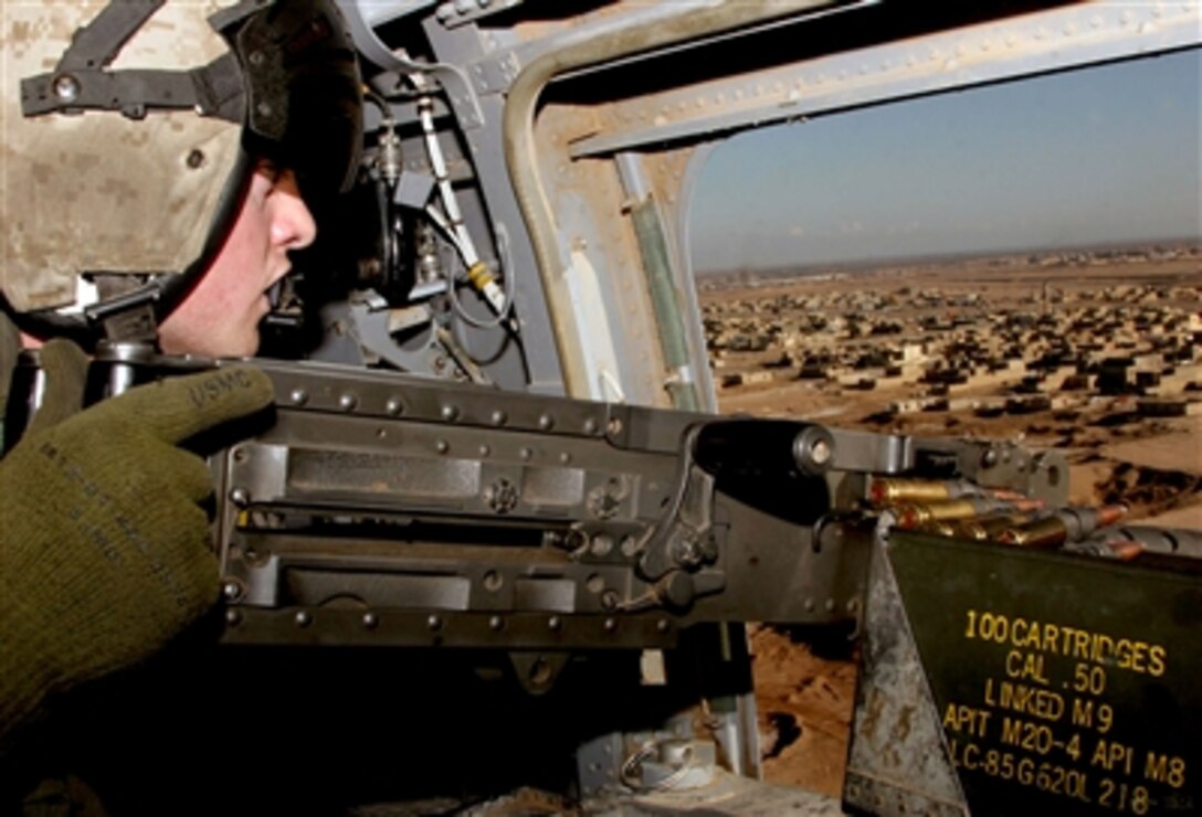 U.S. Marine Corps Lance Cpl. Joe Berry, a CH-46 crew chief with Marine Medium Helicopter Squadron 161, holds a .50-caliber rifle as he looks down on Ramadi, Iraq, during an urgent casualty evacuation mission, Jan. 16, 2006.