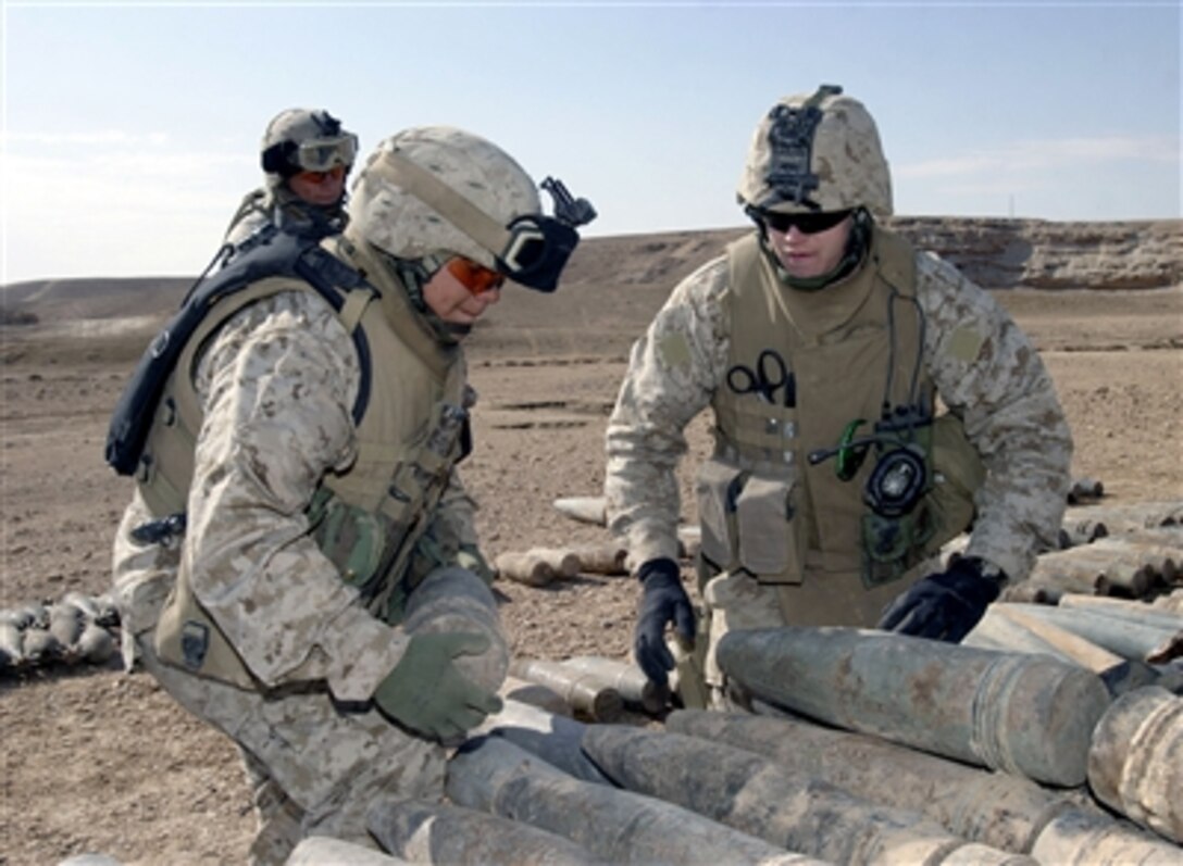U.S. Marines from Lima Company, 3rd Battalion, 1st Marine Regiment, work with U.S. Navy sailors from Explosive Ordnance Disposal Mobile Unit 6, Jan. 15, 2006, to stack ordnance found buried in the outskirts of Barwana, Iraq. The ordnance will be destroyed with C-4 plastic explosives. 