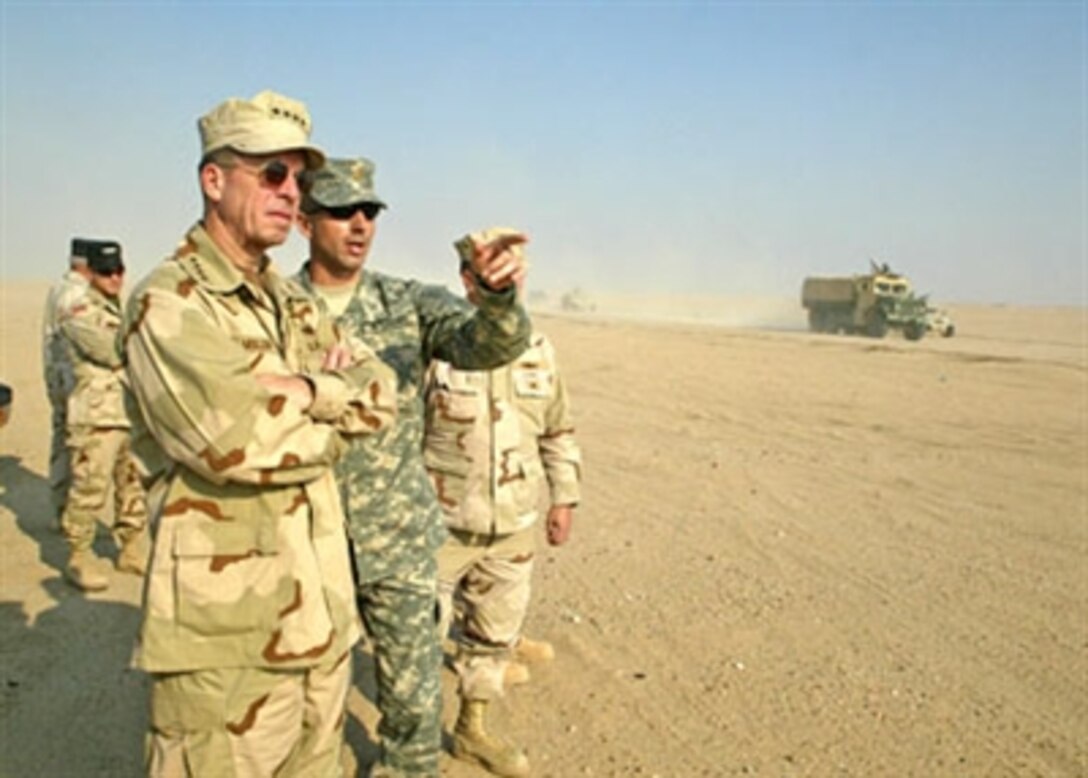 Chief of Naval Operations Adm. Mike Mullen, is briefed by U.S. Marine Corps Maj. Michael A. Konczey, Coalition Forces Land Component Command Training and Operations Combined Arms Maneuvers trainer, as troops drive through the Udairi Range convoy trainer in Kuwait, Jan. 4, 2006.