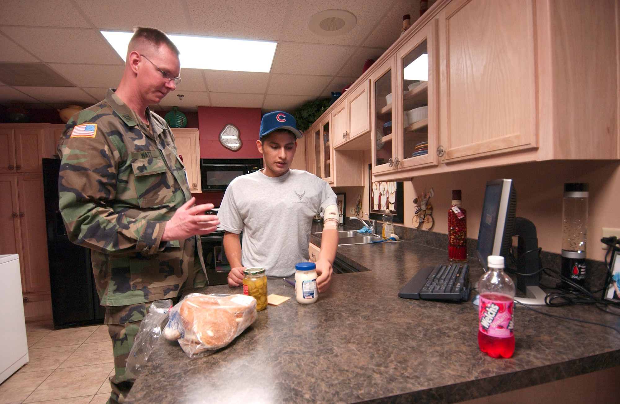 Army Capt. James Watt, an occupational therapist, helps Senior Airman Dan Acosta make a sandwich Thursday, Feb. 23, 2006, in the life skills area of the amputee rehabilitation clinic at Brooke Army Medical Center in San Antonio. A mock apartment in the center helps patients get used to completing common tasks with their prosthetic limbs. (U.S. Air Force photo/Steve White) 