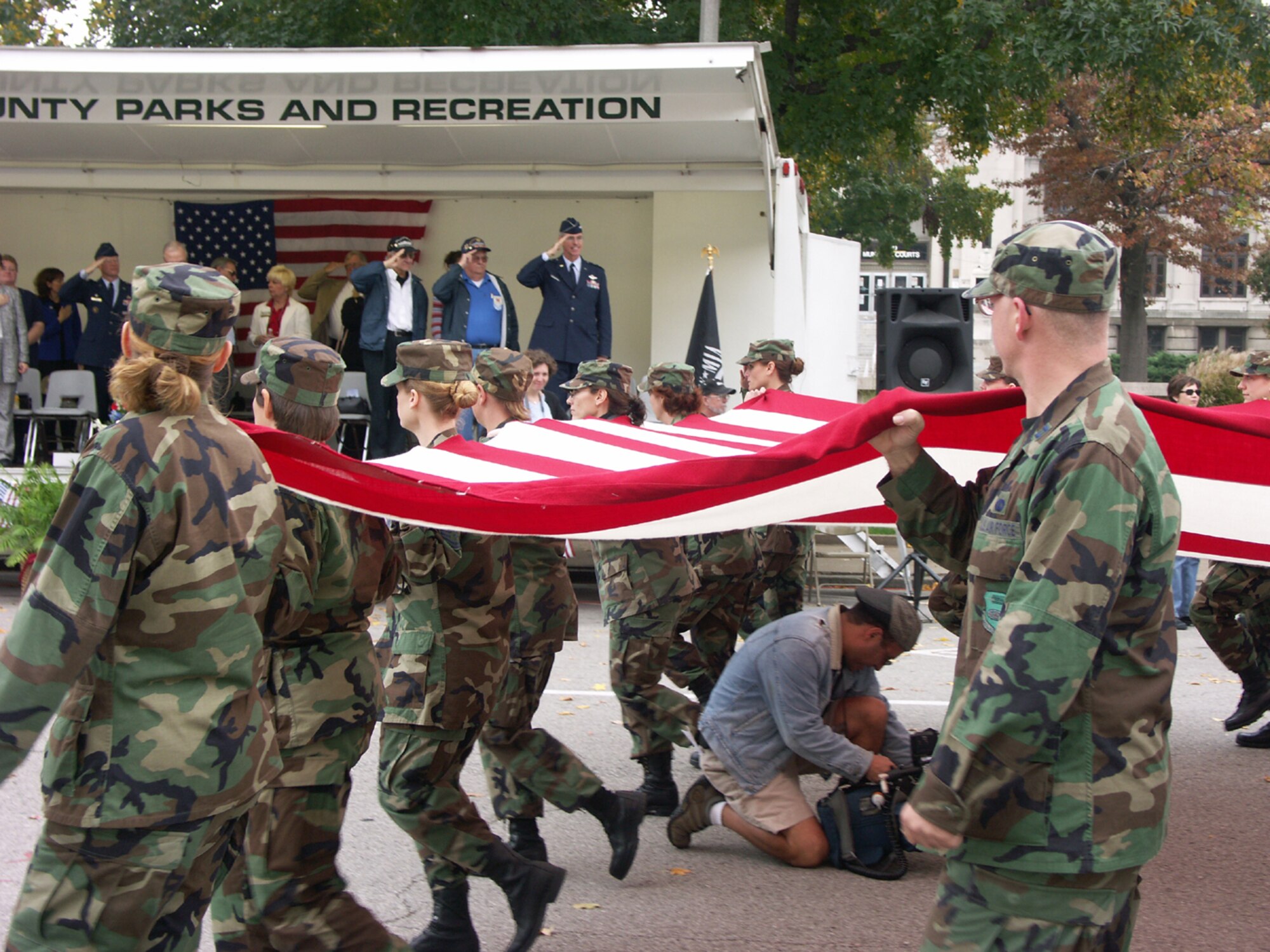 A local news cameraman ducks underneath as members of the Air Force Reserve Command's 932nd Airlift Wing at Scott AFB, Ill., carry an oversized flag during a Veteran's Day parade. Photo by Capt. Stan Paregien.
