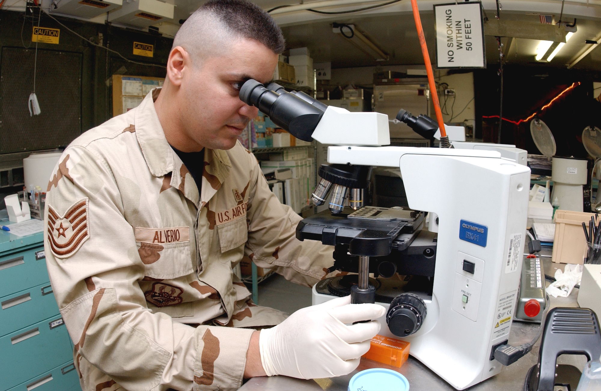 Tech. Sgt. Alex Alverio examines a sample under a high powered microscope at the Air Force Theater Hospital laboratory at Balad Air Base, Iraq. He is deployed here from Wilford Hall Medical Center at Lackland Air Force Base, Texas. (U.S. Air Force photo/Airman 1st Class Jason Ridder)                        