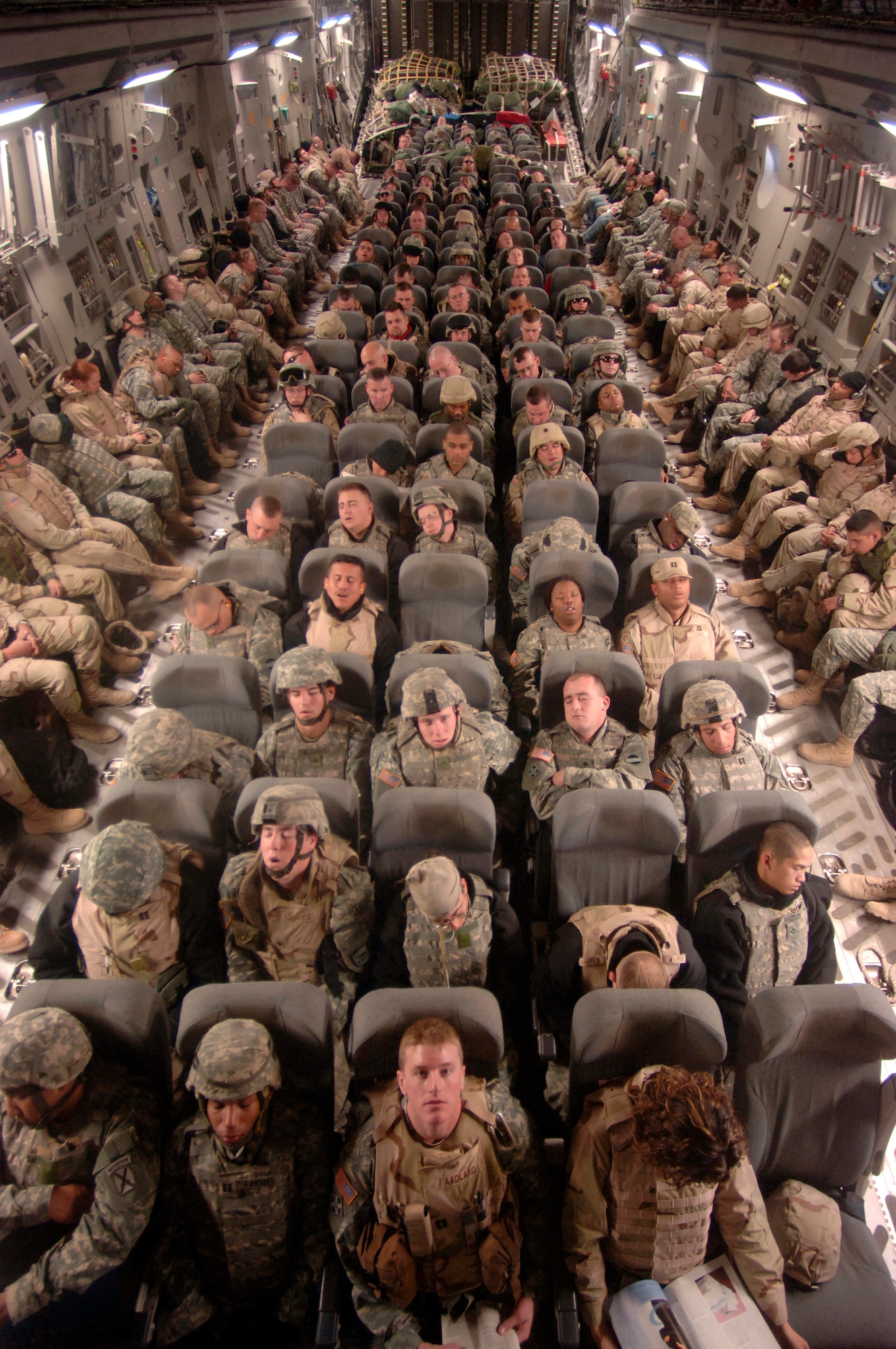 Capt. Erik Aadland (front and center) looks up from his reading during a flight over Iraq Saturday, Feb. 18, 2006.  Most of the passengers were returning to Iraq after a two-week break. The aircraft and crew are from the 315th Airlift Squadron at Charleston Air Force Base, S.C., deployed for one year in Southwest Asia supporting operations Enduring Freedom and Iraqi Freedom. (U.S. Air Force photo/Master Sgt. Lance Cheung)
