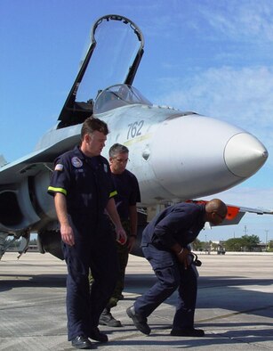 A Canadian crew chief from the 425th Tactical Fighter Squadron shows firefighters from Homestead Air Reserve Base, Fla. how to approach the F-18 and conduct rescue procedures in the event of an emergency.