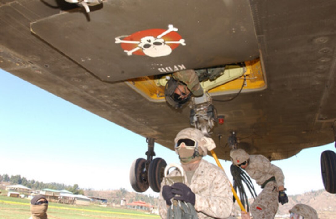 U.S. Marines hunker down under a hovering U.S. Army CH-47 Chinook helicopter as they hook up a sling load of food supplies in Chatter Plain, Pakistan, Feb. 27, 2006. The U.S. military is participating in Pakistani-led relief operations to aid victims of the devastating earthquake that struck the region Oct. 8, 2005. 