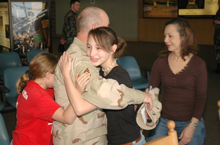 Tech. Sgt. Joseph Moorer, an Air Force reservist assigned to the 38th Aerial Port Squadron, Charleston AFB, S.C., gets a hug from his daughters, Elizabeth (left) and Brittany (right) as he waits (with his wife Tina) to leave for an extended deployment at the Charleston International Airport. (Photo by 1st Lt. Wayne Capps, USAFR)