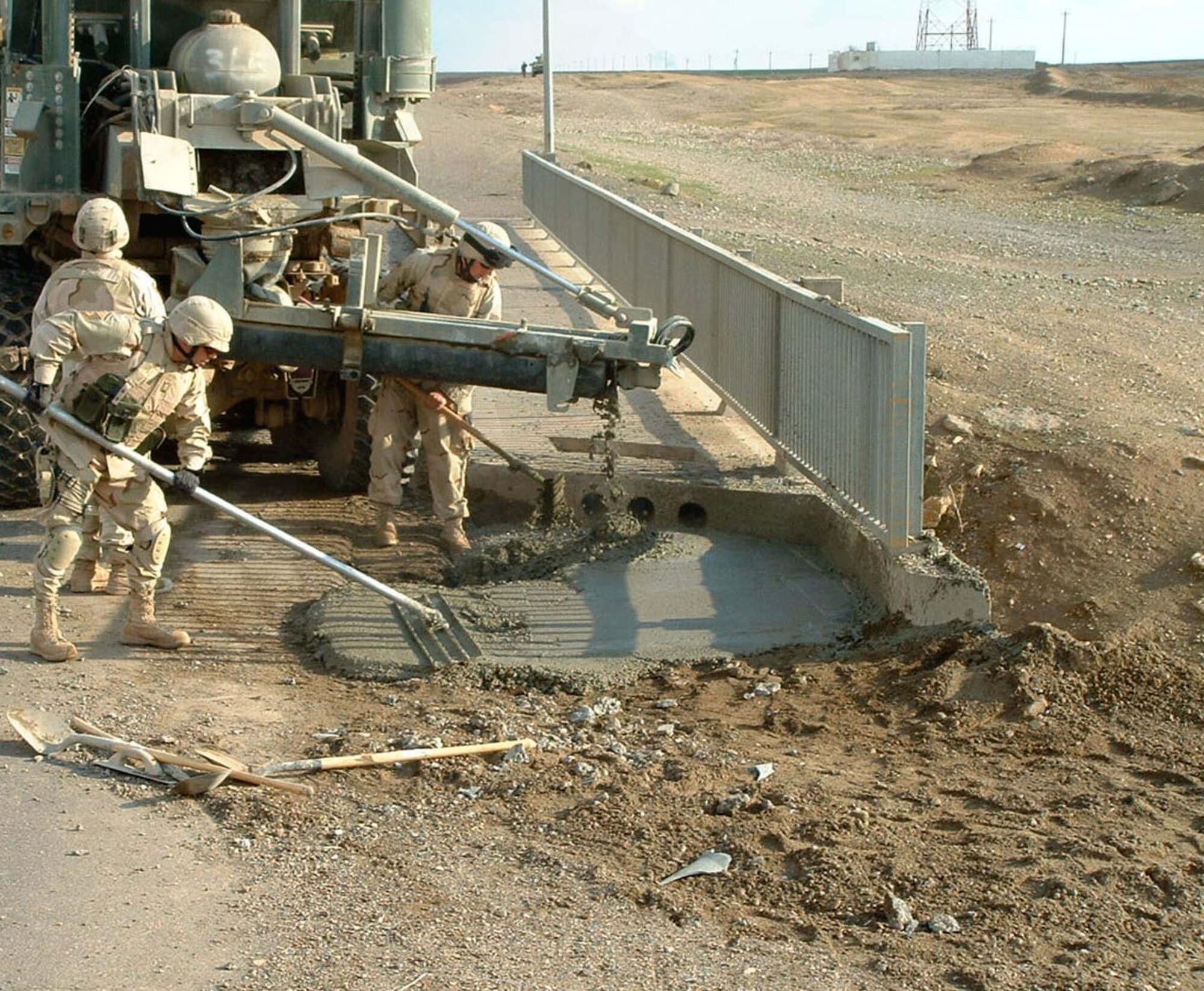 Senior Airmen Adam Chavera and Jason Brashar and Master Sgt. Kirk Kessler pour concrete into a crater on the edge of a bridge from the mobile concrete batch plant. The Airmen, with Detachment 10 of the 732nd Expeditionary Civil Engineer Squadron, were on their first crater repair mission. (Courtesy photo) 
