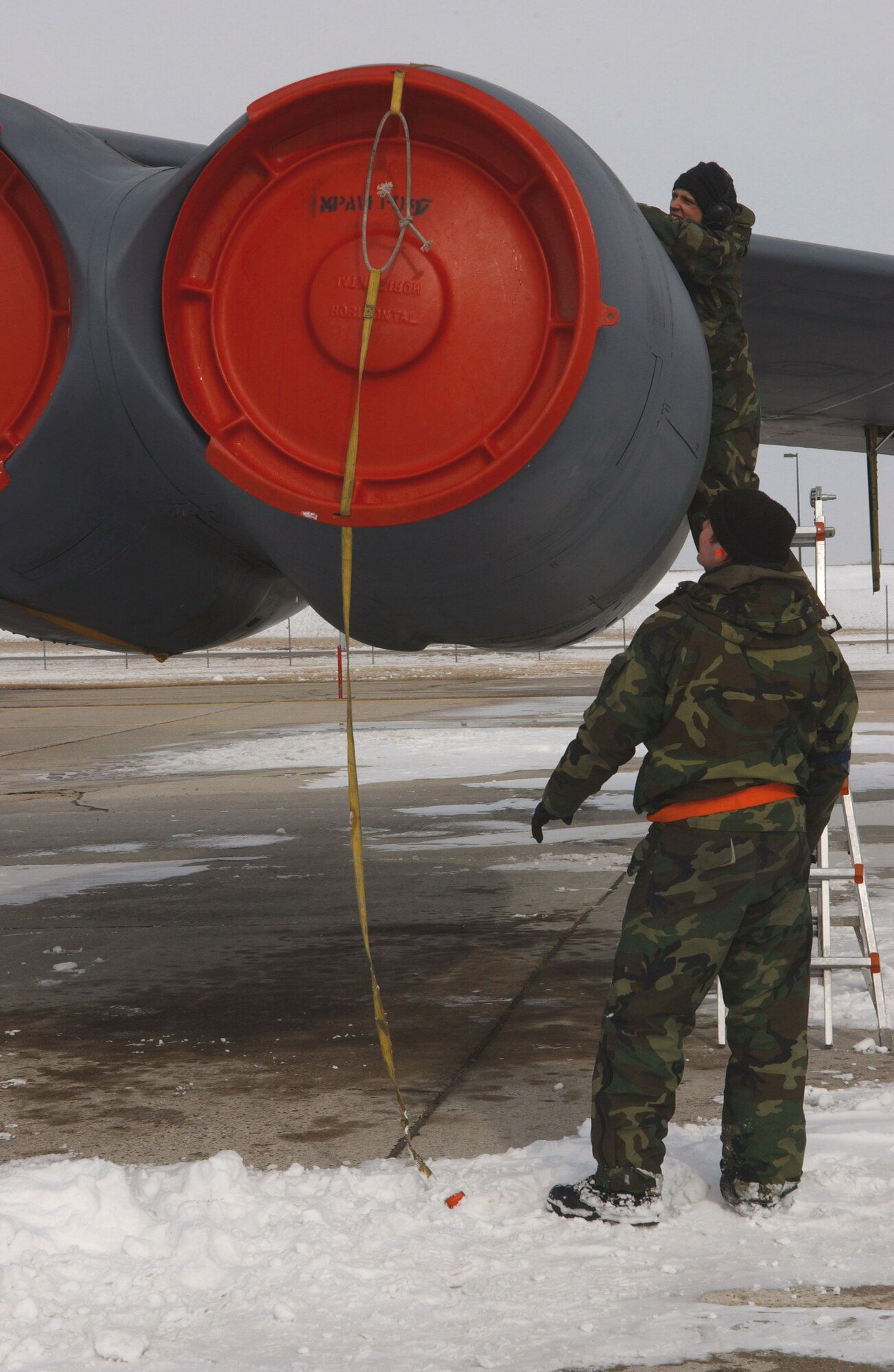 Senior Airman Daniel Williams, top, and Airman 1st Class Michael Schaff secure a B-52H Stratofortress engine cover after an engine run during an alert generation exercise at Minot Air Force Base, N.D., Tuesday, Feb. 28, 2006.  The exercise tested cruise missile loading and aircrew response procedures. Both Airmen are with the 5th Aircraft Maintenance Squadron.  (U.S. Air Force photo/Staff Sgt. Jocelyn Rich)