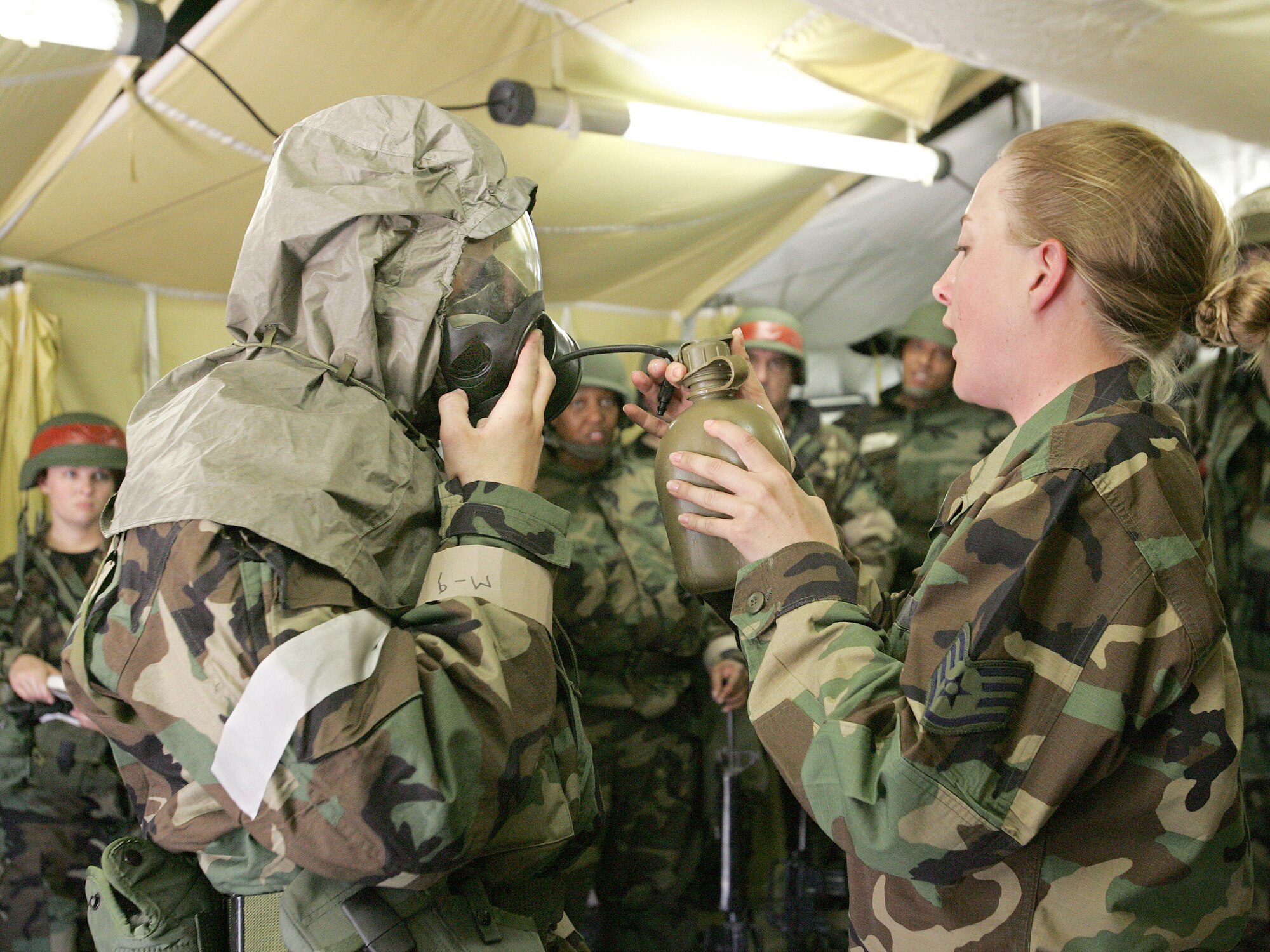 Second Lt. Joshua Daniels receives water from Staff Sgt. Jonnie Gipson during a demonstration of the proper way to hydrate while wearing a gas mask during a contingency exercise at Lackland Air Force Base, Texas, Tuesday, Feb. 28, 2006.  Lieutenant Daniels is with the 37th Services Squadron and Sergeant Gipson is with the 37th Civil Engineer Squadron. (U.S. Air Force photo/Robbin Cresswell)