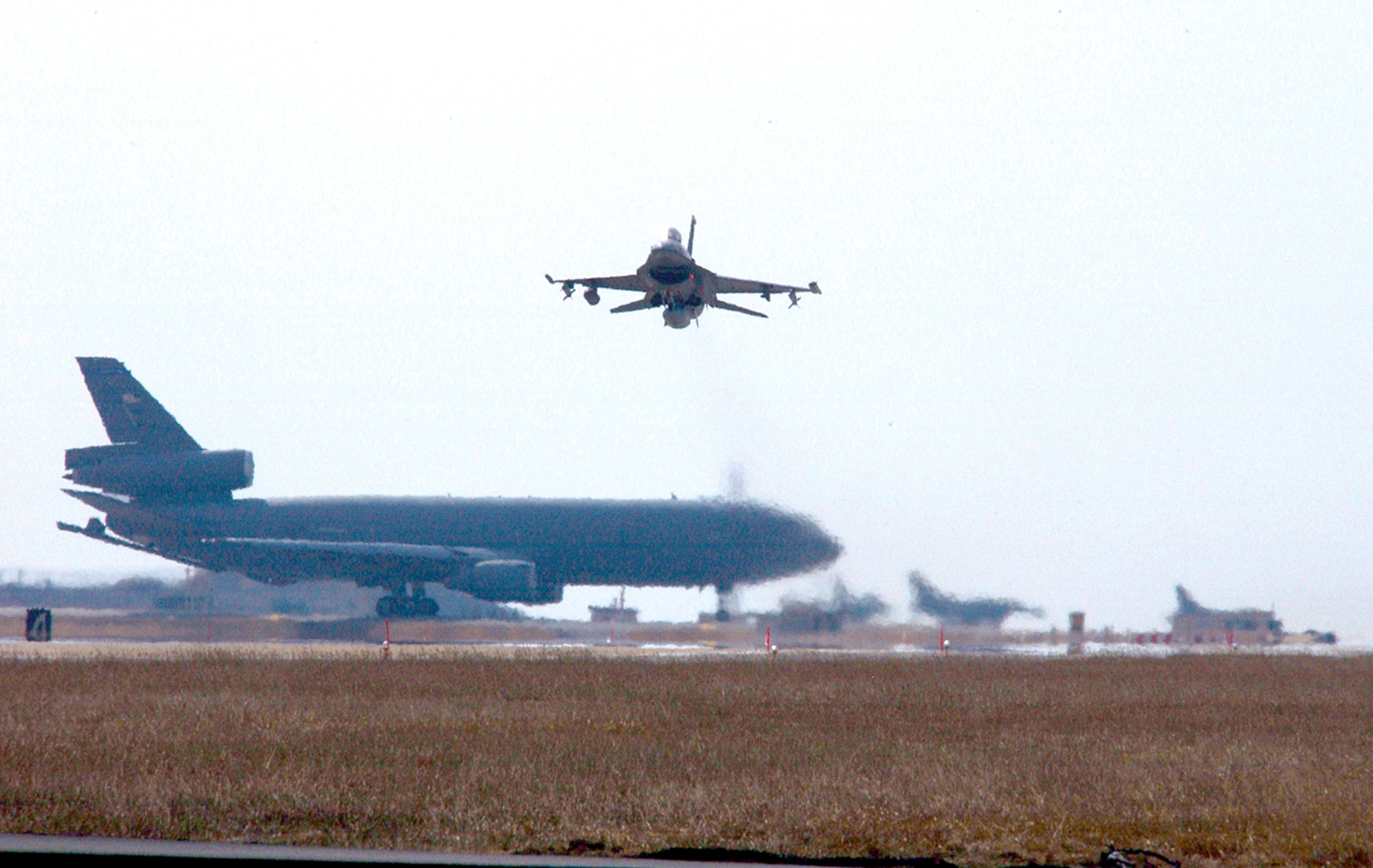 An F-16 Fighting Falcon from the 80th Fighter Squadron lifts off over waiting F-16s and a KC-10 Extender at Kunsan Air Base, South Korea, Thursday, March 2 2006. The 80th FS and 80th Aircraft Maintenance Unit deployed to Singapore Operation Commando Sling, a month-long joint training exercise between the U.S. and Singapore. (U.S. Air Force photo/Senior Airman Joshua Demotts) 