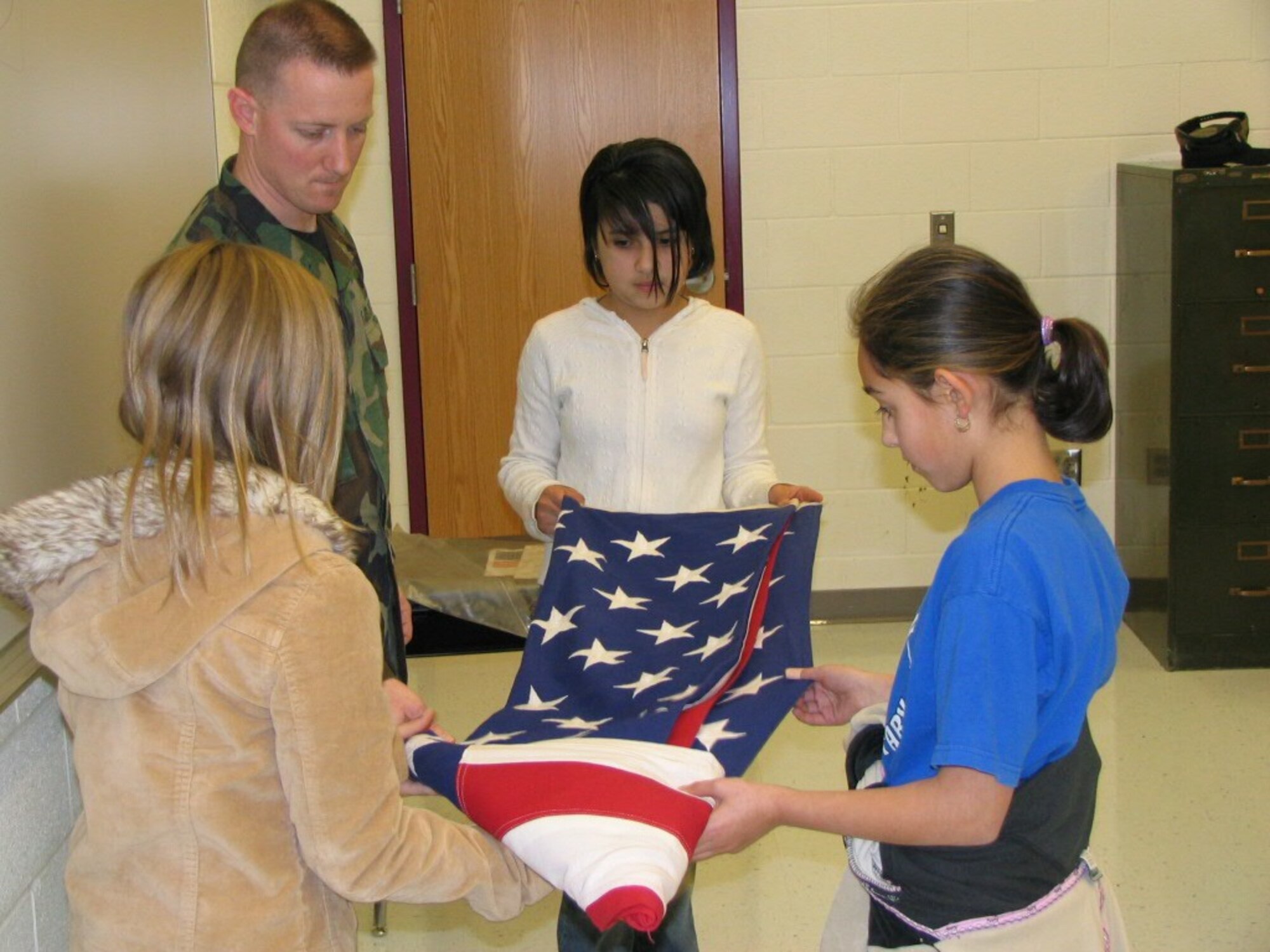 Master Sgt. Rulon Walker of the 419th Fighter Wing Honor Guard, teaches several students at Lincoln Elementary School in Ogden how to properly fold the U.S. flag. The wing's 28-member Honor Guard team regularly visits local schools to educate students on the flag's proper display and respect for the flag. (Photo by Tech. Sgt. Jason Burger)