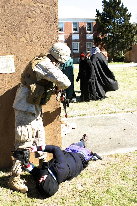 A Marine with Alpha Company, 1st Battalion, 8th Marine Regiment, provides security while role players reach out for help during cultural and combat immersion training on March 5.  A Hollywood production company provided make-up, actors and explosions to help replicate combat conditions during the 24th MEUs Training in an Urban Environment exercise, taking place throughout the Hampton Roads, Va., area.