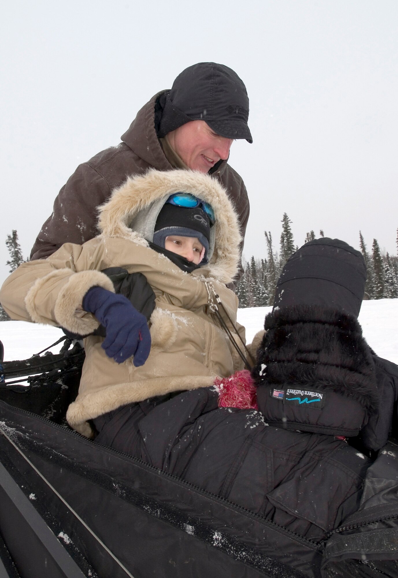 Maj. (Dr.) Thomas Knolmayer helps 10-year-old Katie Powell out of a sled after giving her a ride with his Iditarod sled dog team. Katie is the daughter of Senior Master Sgt. Chris Powell of Travis Air Force Base, Calif., and has Ewing's Sarcoma, a rare bone cancer. (U.S. Air Force photo/Tech. Sgt. Keith Brown)