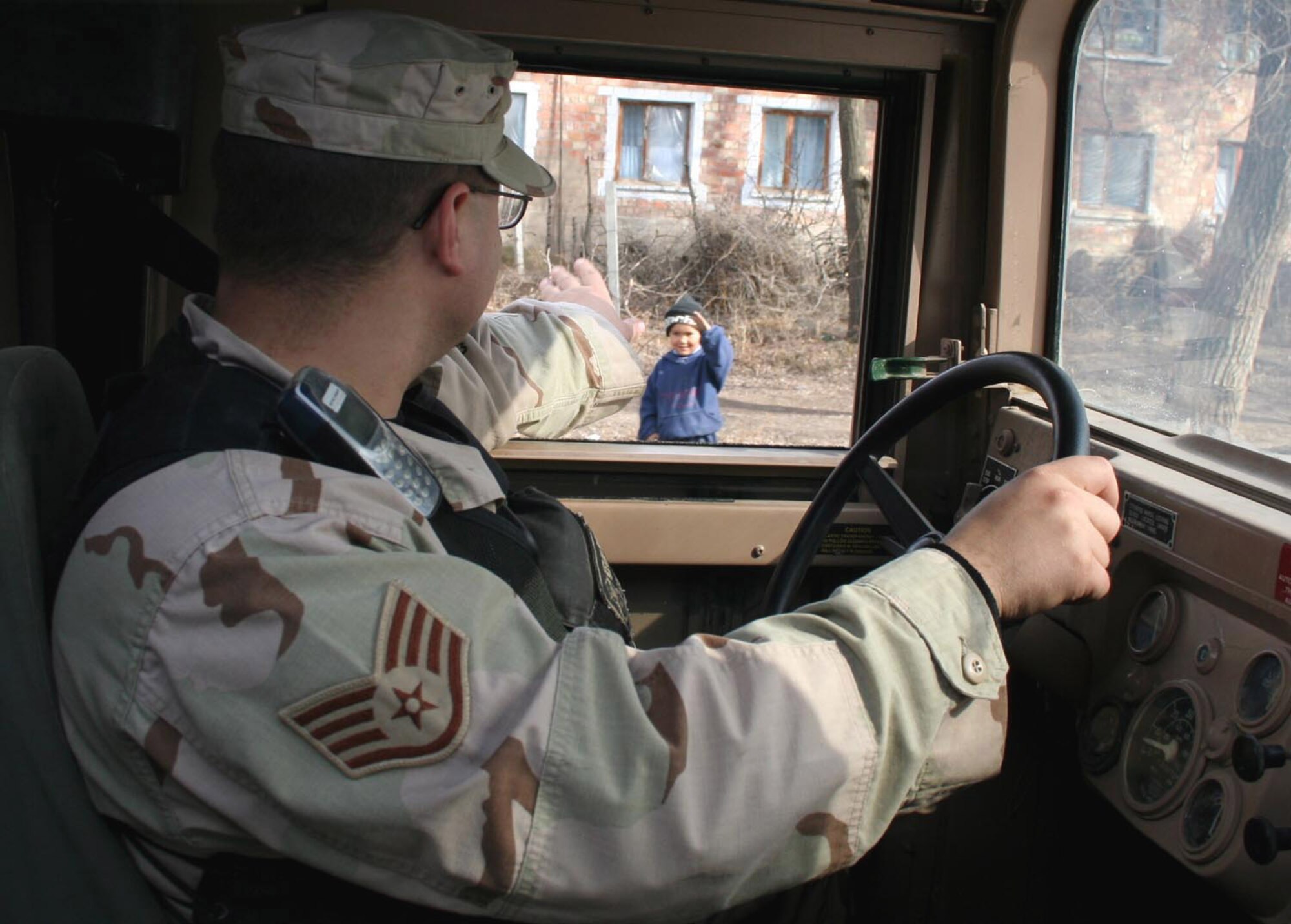 A local boy waves at Staff Sgt. Kevin Bovee as he passes on a saber patrol outside of Manas Air Base, Kyrgyzstan, Friday, March 3, 2006. Most villagers have become accustomed to the patrols and greet them with a friendly nod or wave as they pass. Sergeant Bovee is deployed from Wright-Patterson Air Force Base, Ohio. (U.S. Air Force photo/Staff Sgt. Lara Gale) 

