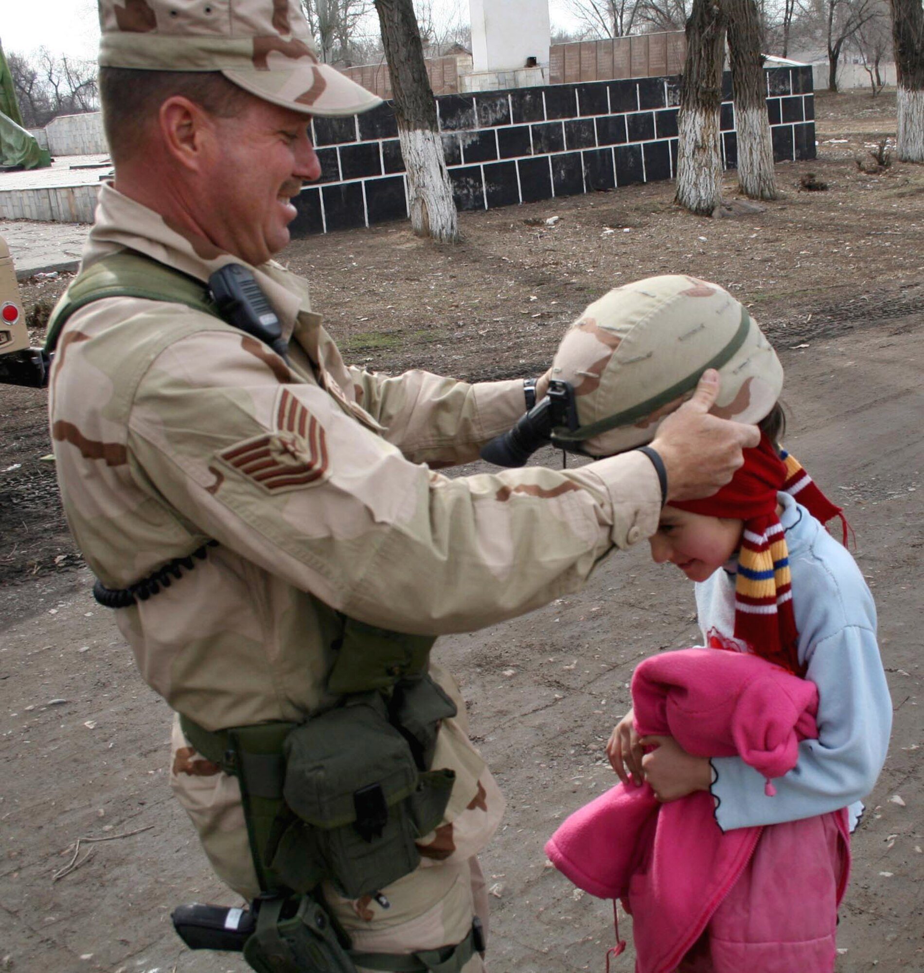 Tech. Sgt. Edward Sileo interacts with a child during a saber patrol outside of Manas Air Base, Kyrgyzstan, Friday, March 3, 2006. Sergeant Sileo recently deployed here from Homestead Air Reserve Base, Fla., and is with the 376th Expeditionary Security Forces Squadron. (U.S. Air Force photo/Staff Sgt. Lara Gale) 

