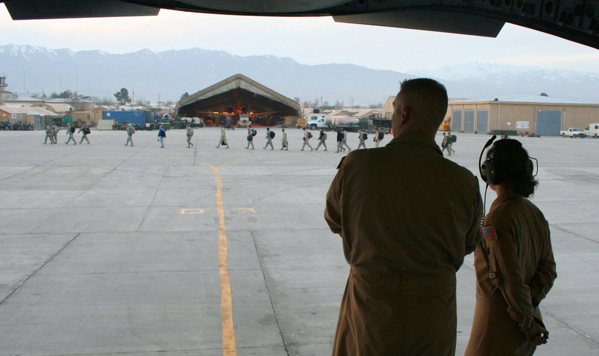 Airmen 1st Class Jesse Doyle and Suzanne Van Elk, loadmasters, watch Soldiers make their way across the flightline after disembarking the C-17 Globemaster III that completed the final leg of their journey to Bagram Air Base, Afghanistan. Airman Doyle and Airman Van Elk are deployed from McChord Air Force Base, Wash. (U.S. Air Force photo)