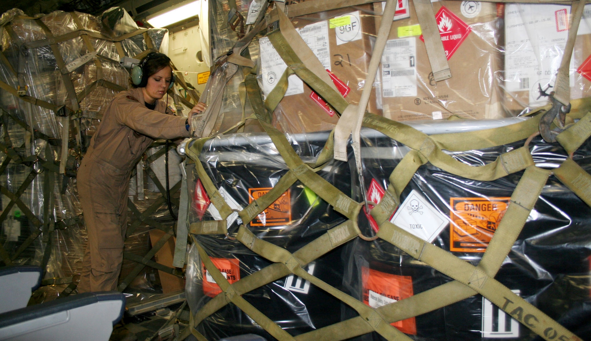 Airman 1st Class Suzanne Van Elk gets a pallet rolling for download from a C-17 Globemaster III at Manas Air Base, Kyrgyzstan. When cargo includes hazardous material, like the volatile methanol on this pallet, loadmasters plan the cargo load around it, keeping incompatible cargo away. Airman Van Elk is deployed from McChord Air Force Base, Wash. (U.S. Air Force photo)