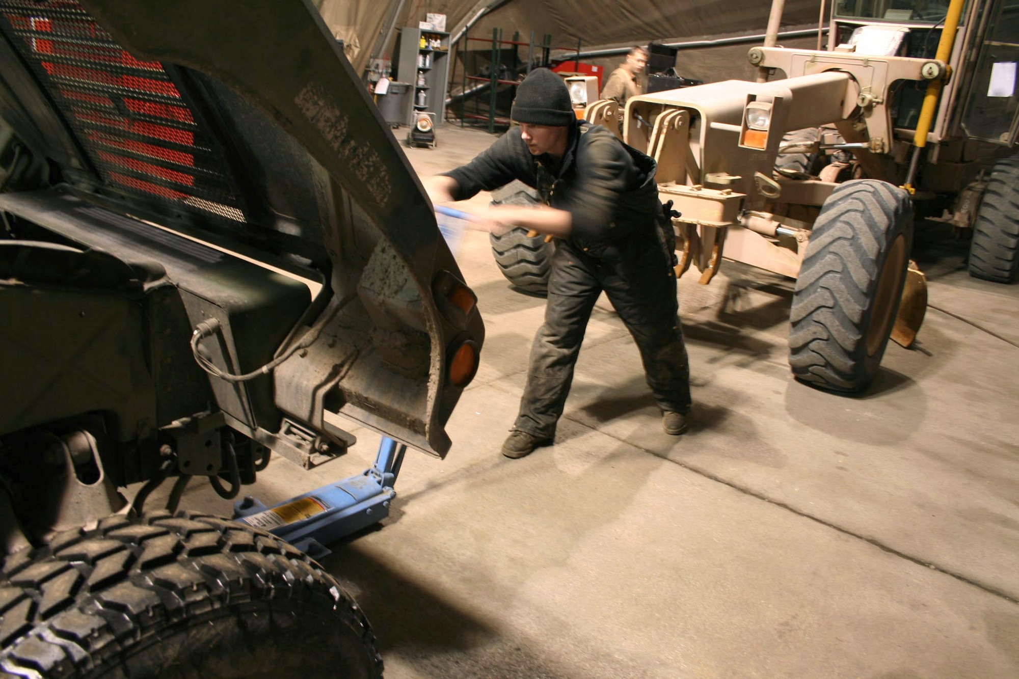 Senior Airman Matthew Goodson jacks a Humvee up onto lifts at Manas Air Base, Kyrgyzstan, to change out an engine part. (U.S. Air Force photo/Staff Sgt. Lara Gale)