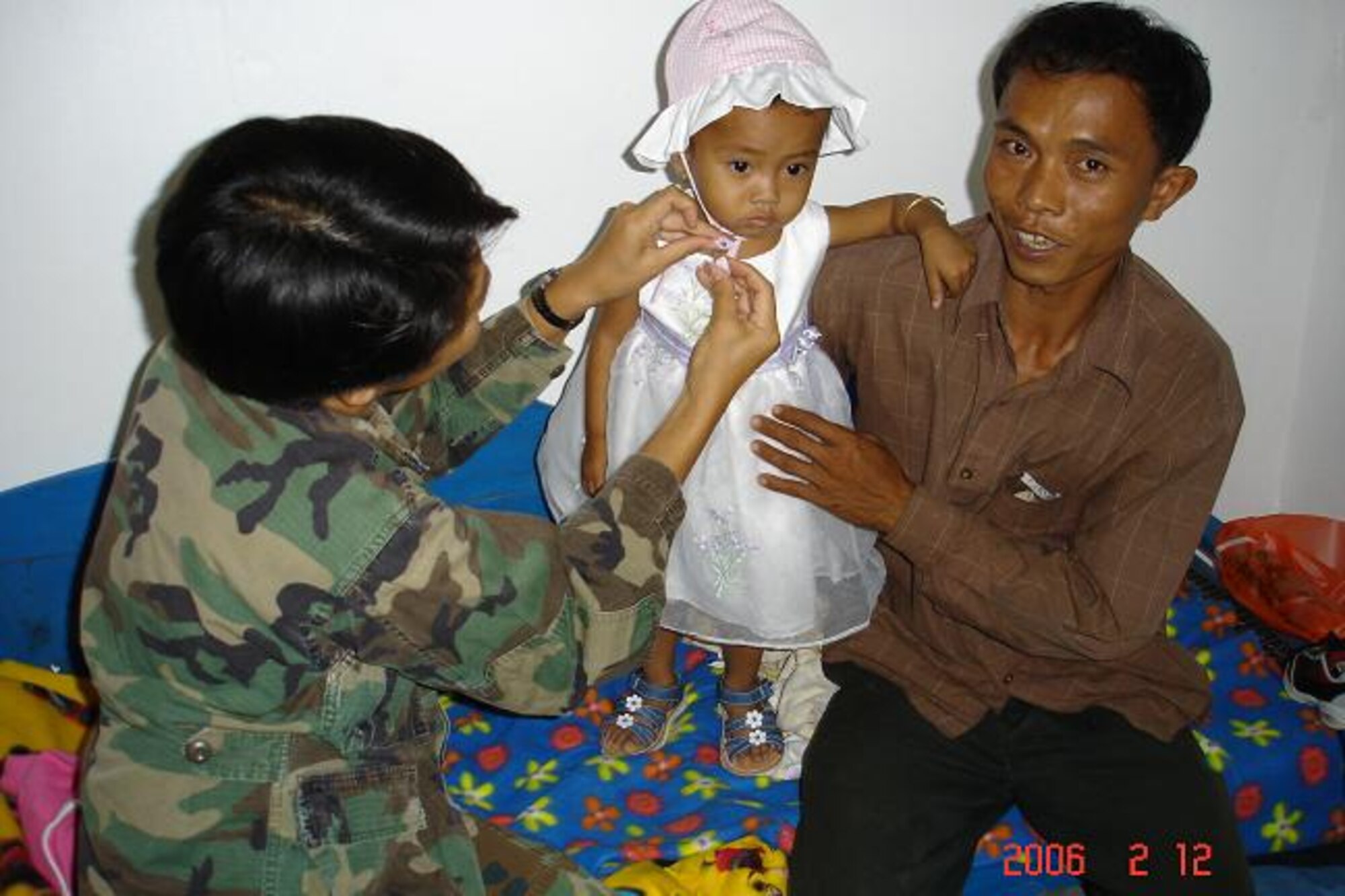 CAMBODIA -- An airman from Pacific Air Forces Internal Health Affairs fascens a bonet on a local youth. During a recent medical mission, Airmen reached out to locals with donated clothing, toys, school kits, hygiene kits, and much more. During the mission, the team screened more than 13,000 patients and treated approximately 3,500 patients. The donated items helped approximately 2,000 children.