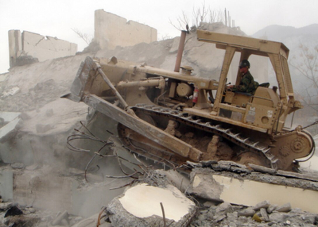 U.S. Navy Seabee Nathan Luetjen operates a bulldozer to demolish an unsafe building in Muzaffarabad, Pakistan, on Feb. 24, 2006. The Department of Defense is supporting the State Department by providing disaster relief supplies and services following the massive earthquake that struck Pakistan and parts of India and Afghanistan. Luetjen, a Navy equipment operator assigned to Naval Mobile Construction Battalion 4, Detachment Pakistan, is razing the building to prevent injuries to the Pakistani people. 