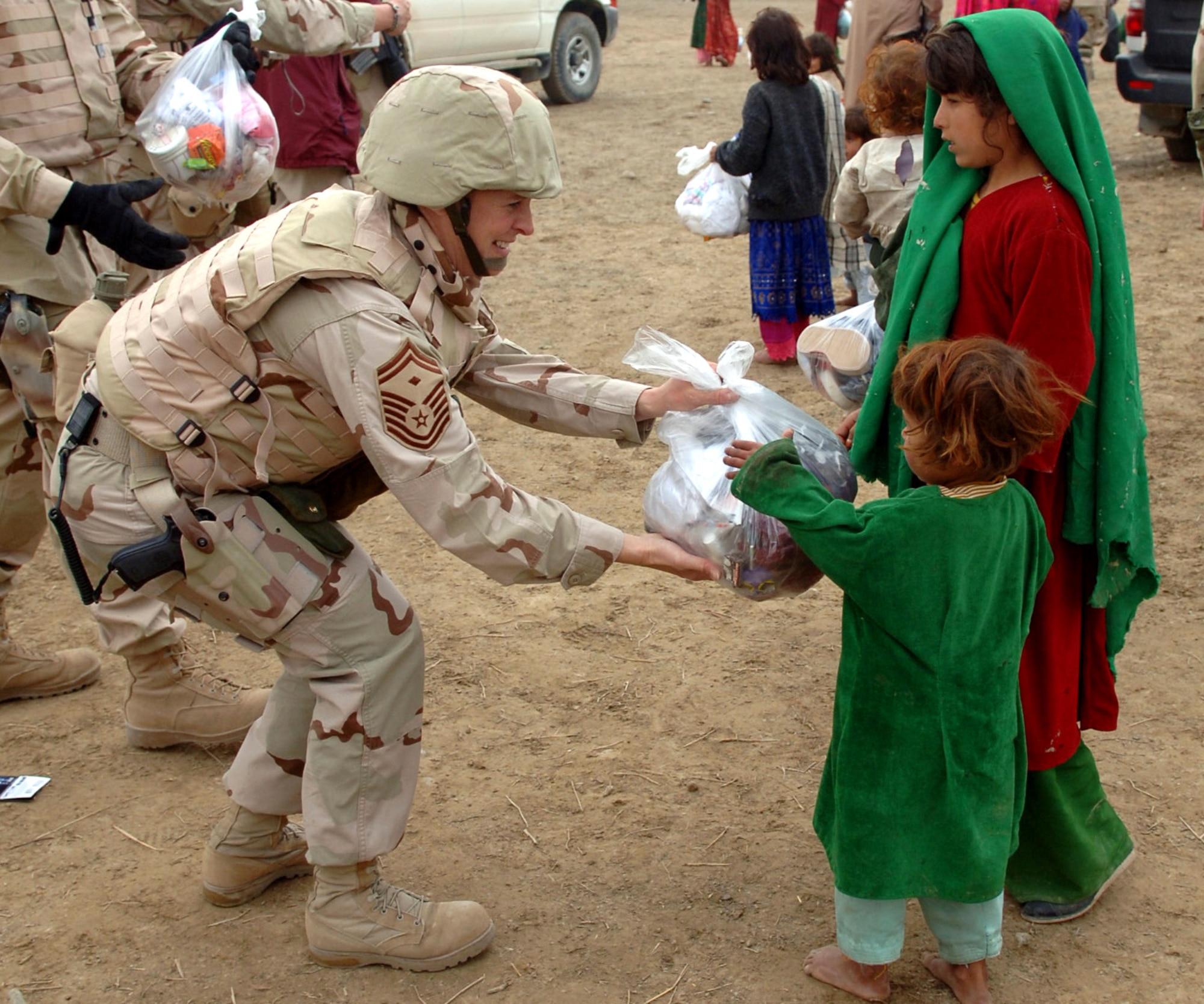 Senior Master Sgt. Diana Brown gives clothes to two Afghan girls during a recent Adopt-A-Village visit in Parwan Province, Afghanistan. More than 40 Airmen participated in giving the village of Gadia more than 400 bags of clothes, hygiene items and school supplies. Sergeant Brown is the 455th Expeditionary Aircraft Maintenance Squadron first sergeant at Bagram Air Base, Afghanistan. She is deployed from the Ohio Air National Guard's 179th Airlift Wing. (U.S. Air Force photo/Staff Sgt. Jennifer Redente) 