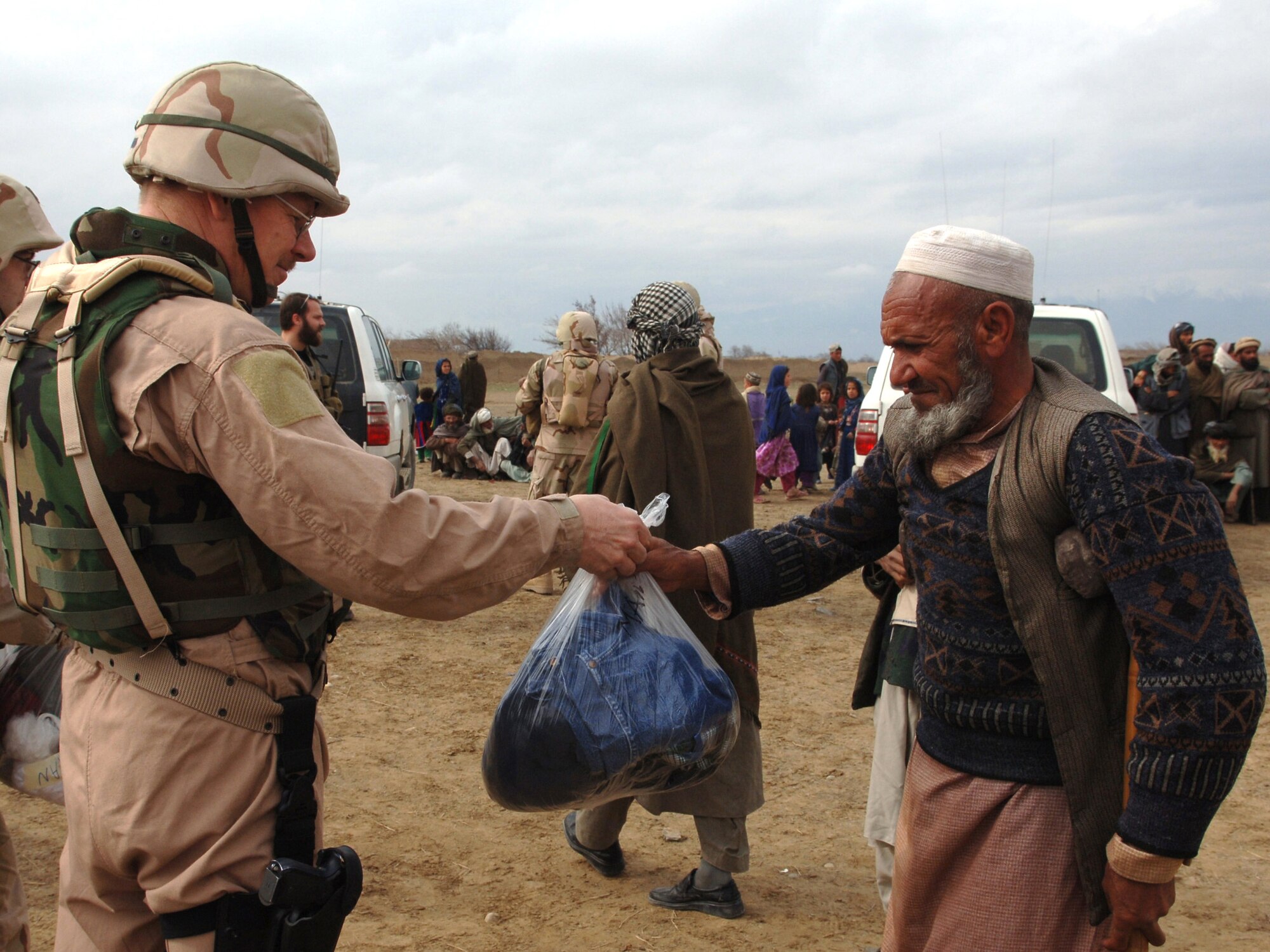 Tech. Sgt. John Strothenke hands a village elder a bag of clothing during a recent Adopt-A-Village visit to Gadia, Afghanistan. Sergeant Strothenke is an independent duty medical technician assigned to the 455th Expeditionary Fighter Squadron at Bagram Air Base, Afghanistan. He is deployed from Eielson Air Force Base, Alaska. (U.S. Air Force photo/Staff Sgt. Jennifer Redente) 