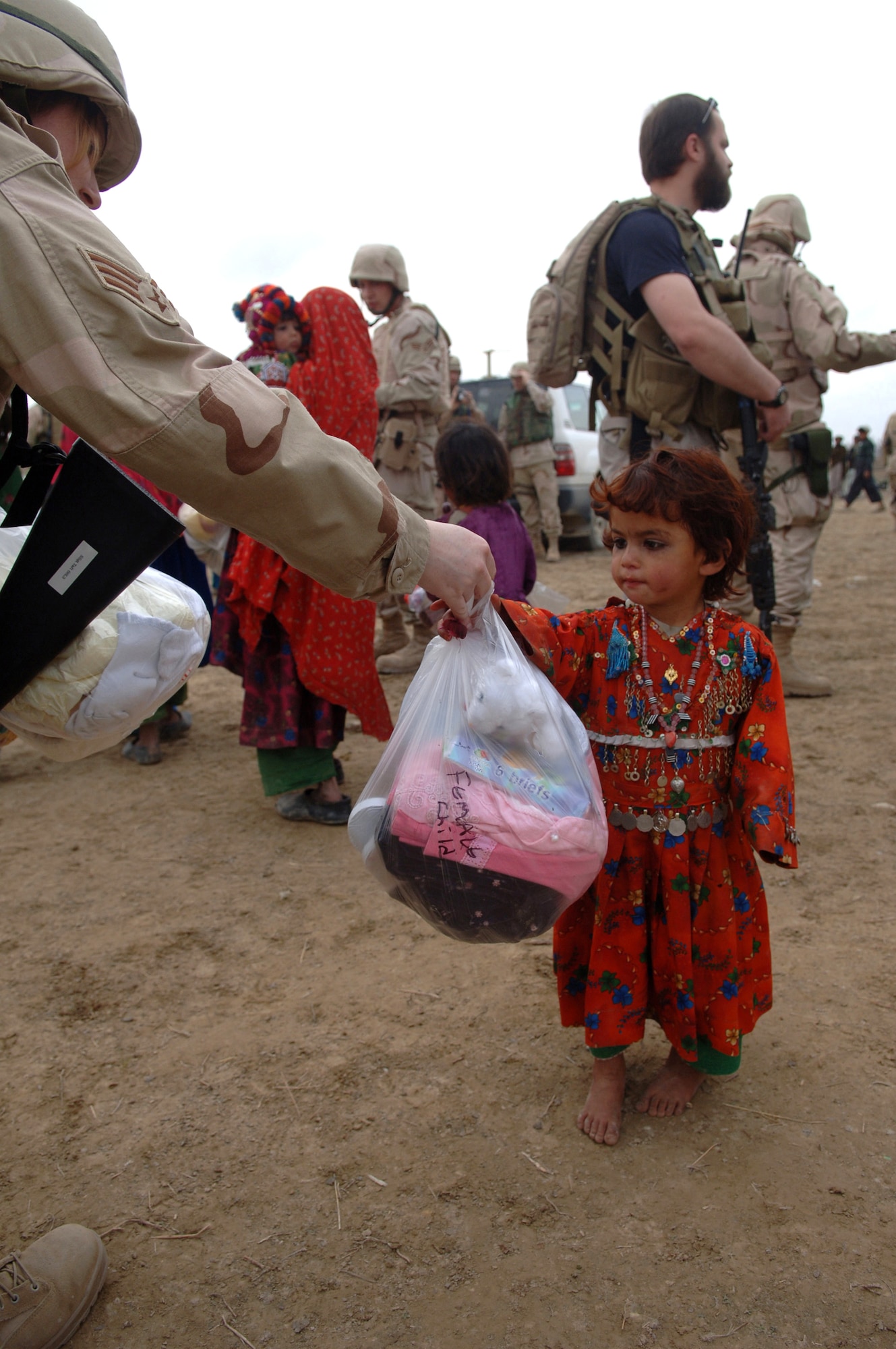 Senior Airman Jennifer Travise hands a young girl from Gadia, Afghanistan, a bag of basic necessities during a recent Adopt-A-Village visit. Airman Travise is an ammunitions accountability clerk with the 455th Expeditionary Aircraft Maintenance Squadron at Bagram Air Base, Afghanistan. She is deployed from Eielson Air Force Base, Alaska. (U.S. Air Force photo/Staff Sgt. Jennifer Redente) 