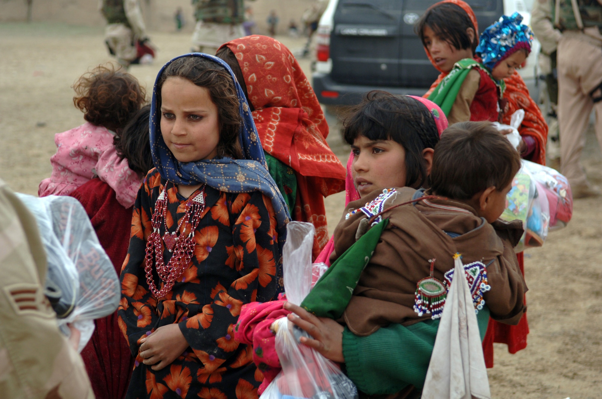 Young girls are given clothes during a recent Adopt-A-Village visit in Gadia in the Parwan Province, Afghanistan. Airmen with the 455th Air Expeditionary Wing sorted through donations and filled more than 400 bags with clothes, shoes, school supplies and hygiene items, which were handed out to the Afghans. (U.S. Air Force photo/Staff Sgt. Jennifer Redente) 