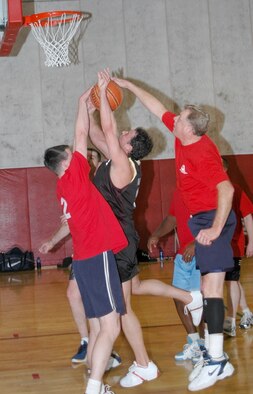 Trent Ward, center, has his shot sandwich blocked by DOD Policemen Benjamin Durr, left, and Tim Spangler during the championship game of the annual basketball tournament at Grissom Air Reserve Base, Ind. The cops handcuffed the 434th Communications Squadron 72-52 in the final game of the double-elimination tournament to take home the trophy.