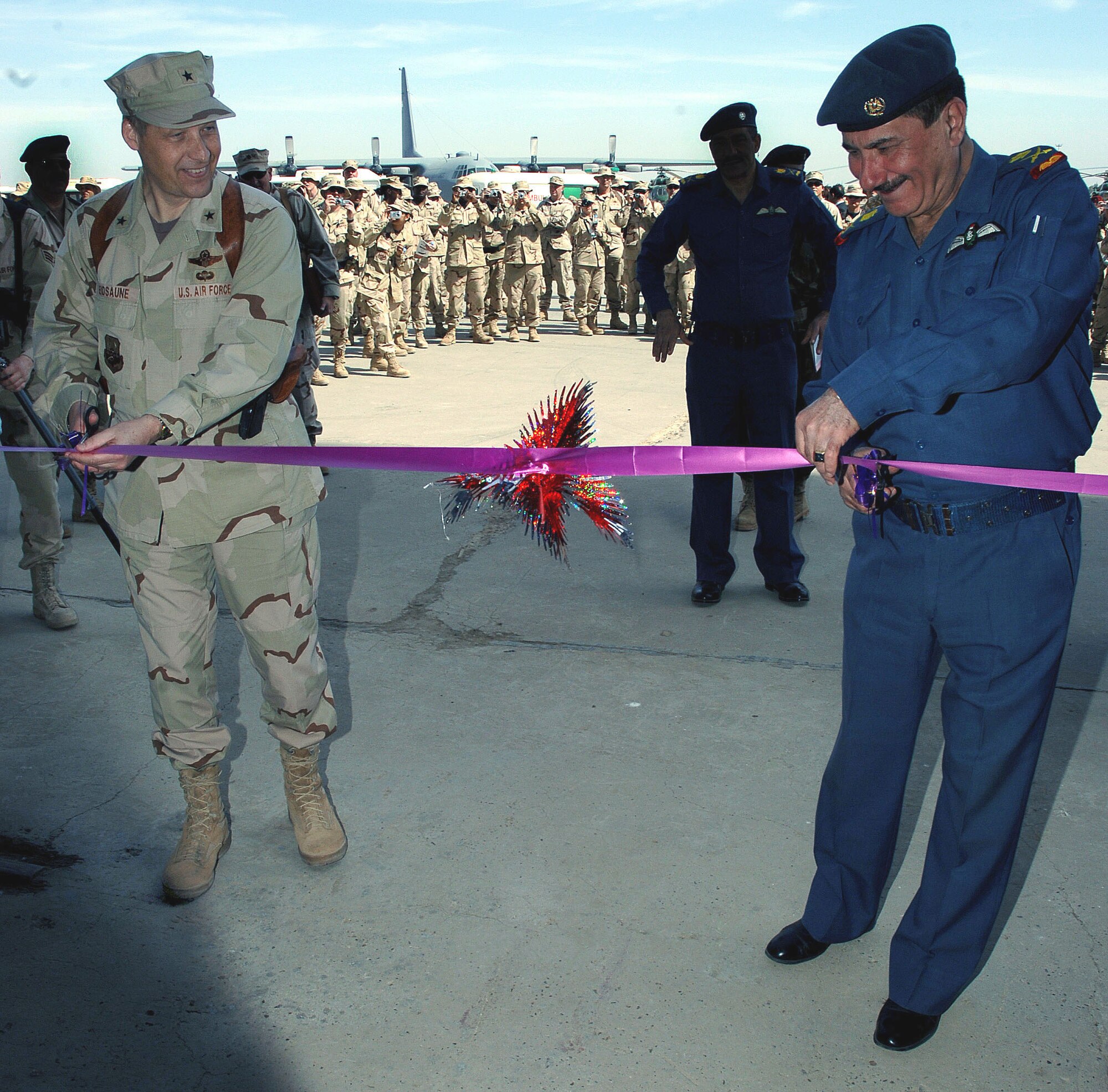 Brig. Gen. David Eidsaune and Maj. Gen. Kamal Barzanjy cut the ribbon at a formal ceremony opening New Al Muthana Air Base, Iraq, Tuesday, March 7, 2006. The event culminated more than a year of training by U.S. Airmen with the Multinational Security Transition Command Coalition Air Force Transition Team. This is the first post-Saddam Hussein era Iraqi Air Force base and squadron. General Eidsaune is the director Air Component Coordination Element, Multinational Forces-Iraq. General Barzanjy is the Iraqi Air Force chief of staff. (U.S. Air Force photo/Master Sgt. Will Ackerman)