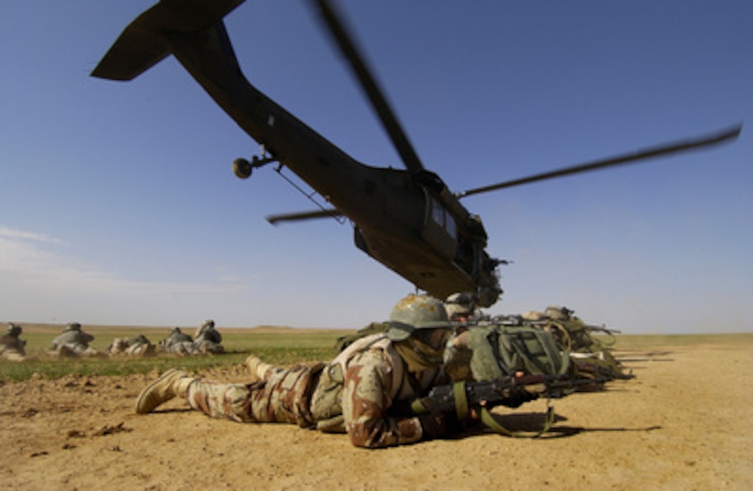 Iraqi army and U.S. Army soldiers secure a landing zone after departing from a UH-60 Black Hawk helicopter during an assault mission in Iraq near the Syrian border on March 6, 2006. 