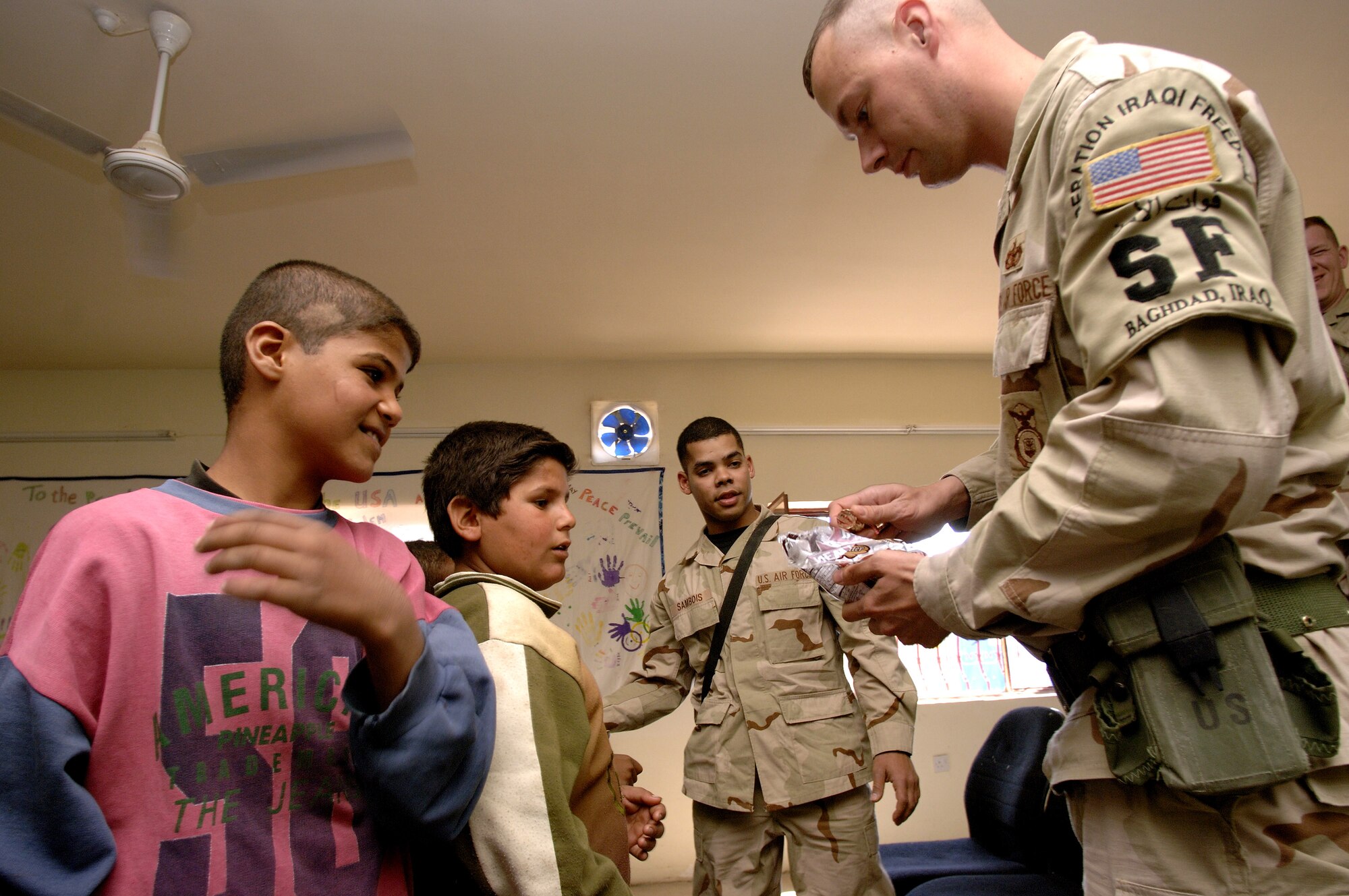 Staff Sgt. Brian Newton (right) and Senior Airman Argenis Sambois entertain children waiting to see a medic at the Radhwaniya Medical Clinic Outreach Program. Several times a week, volunteers meet at the facility on the edge of the Baghdad International Airport area and support the medical needs of civilians. (U.S. Air Force photo/Master Sgt. Lance Cheung)