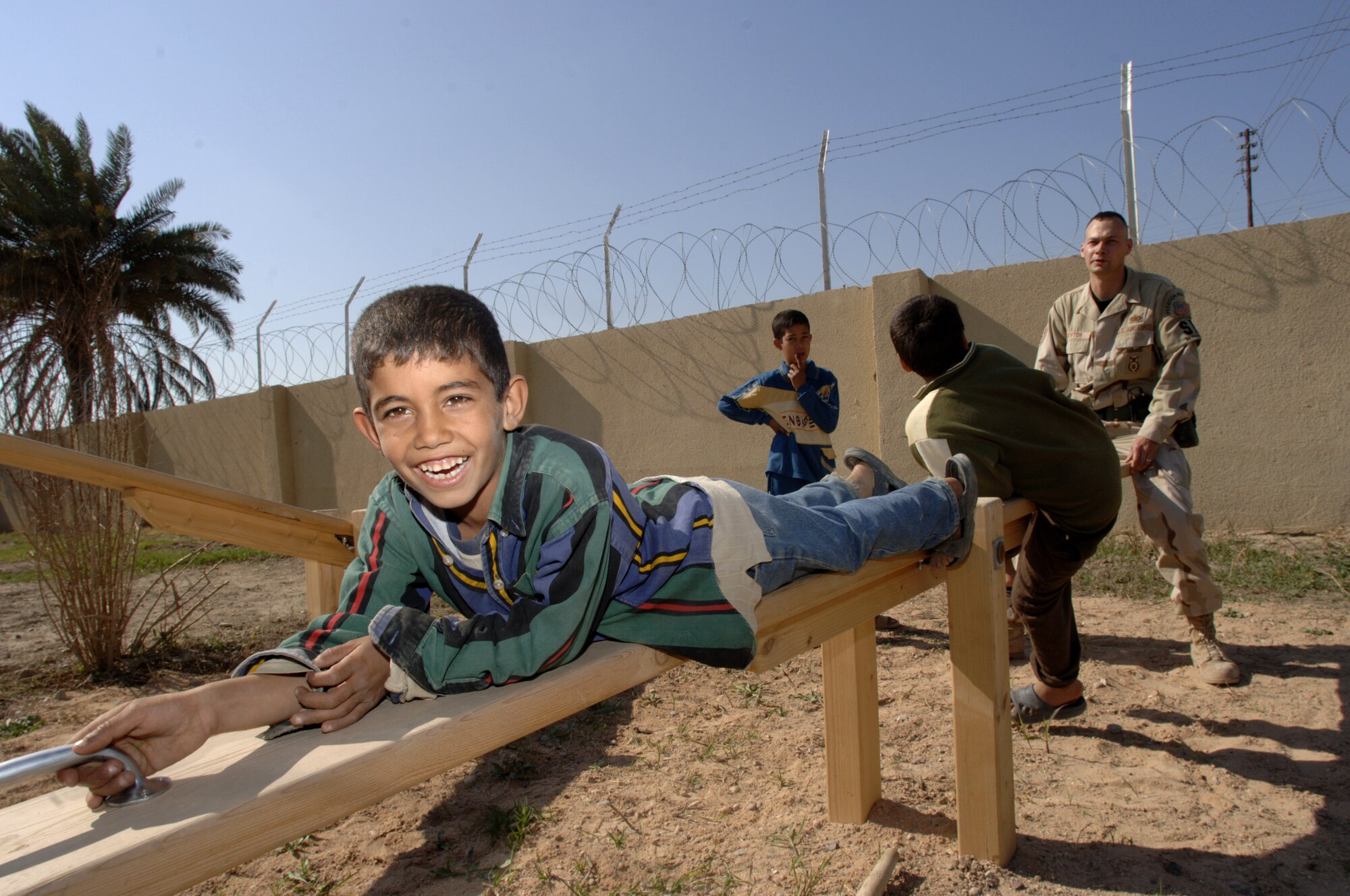 Staff Sgt. Brian Newton plays with Iraqi children at the playground outside the Radhwaniya Medical Clinic. Sergeant Newton is assigned to the 447th Expeditionary Security Forces Squadron, Sather Air Base, Iraq. Several times a week volunteers meet at the facility on the edge of the Baghdad International Airport area and support the medical needs of civilians. (U.S. Air Force photo/Master Sgt. Lance Cheung) 