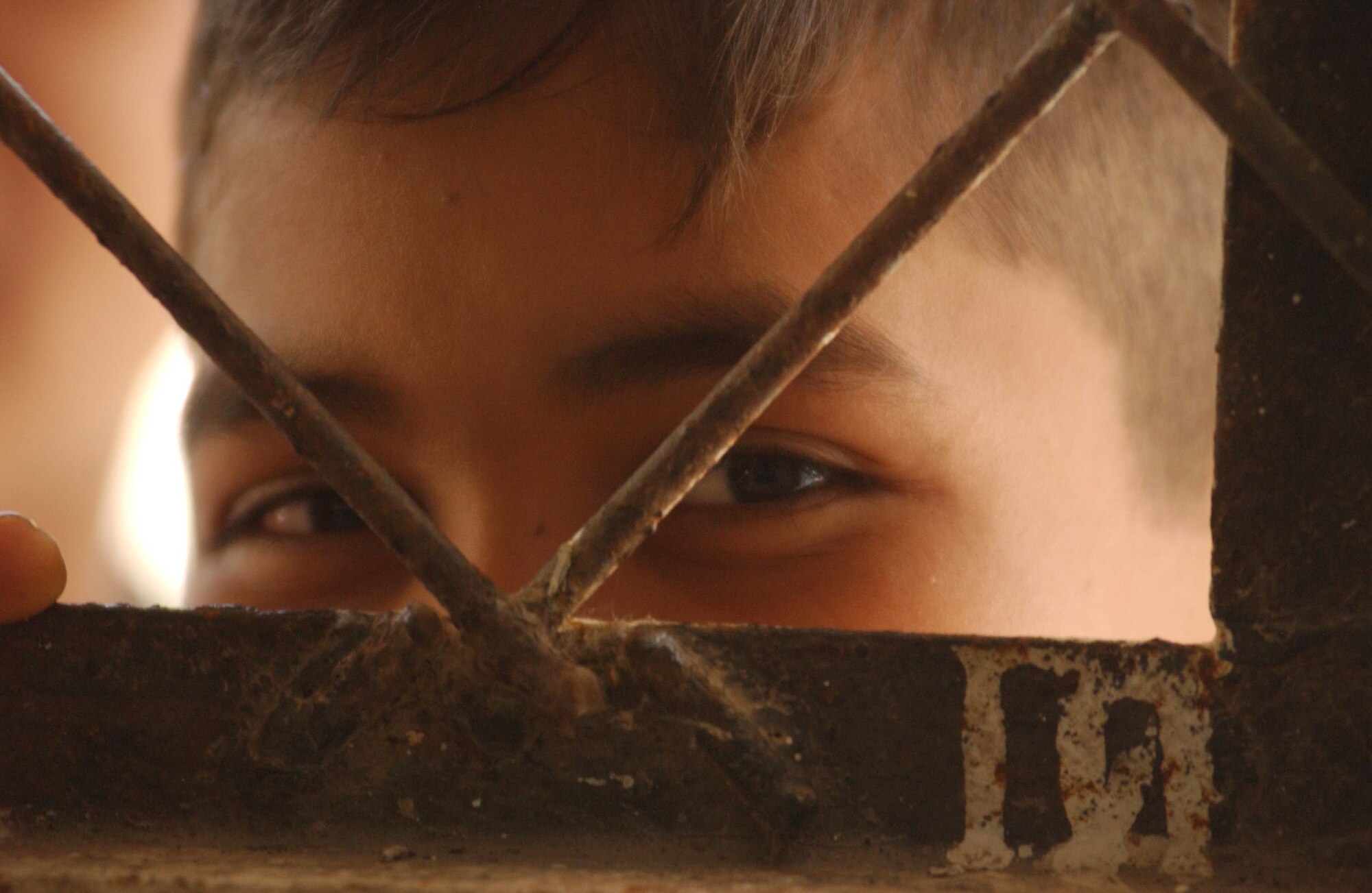 A young El Salvadoran boy peeks through the wire window of a classroom at the schoolhouse where Air Force Reserve Airmen consult with patients about their ailments. 