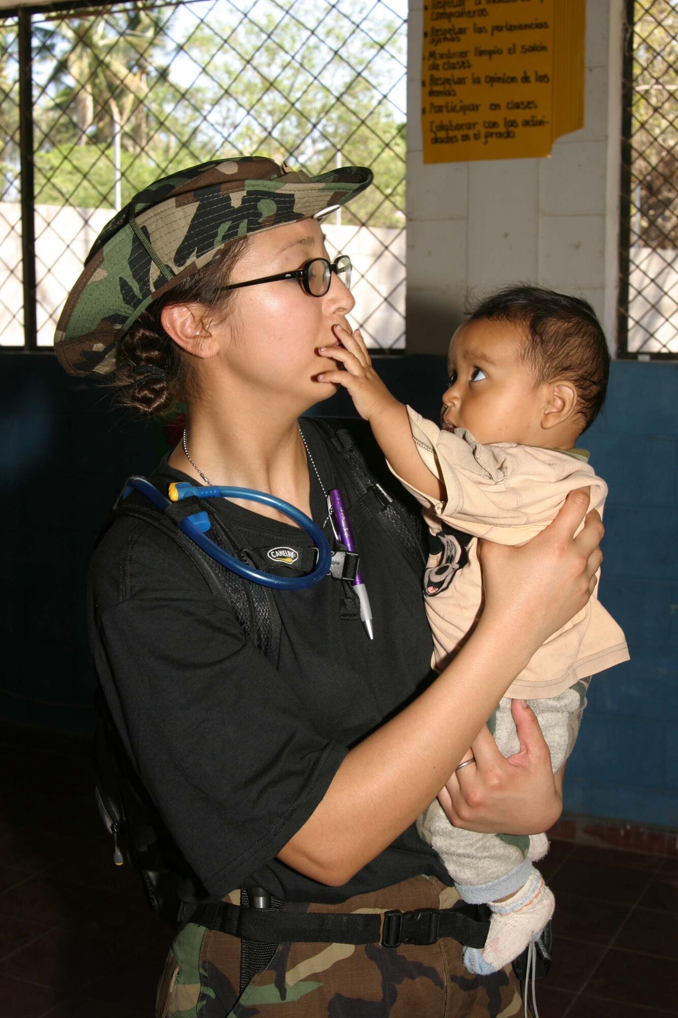 Staff Sergeant Jennifer Yoon, Air Force Reserve 349th Aerospace Medicine Squadron medical technician from Travis Air Force Base, holds the daughter of an El Salvadoran mother who took her three children to see the  pediatrician for a check-up.  