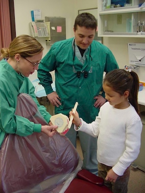 Britannia Scott [right], daughter of Vicky and Tech. Sgt. Russell Scott, 60th Aerial Port Squadron, practices proper teeth brushing techniques with the assistance of dentists Dr. [Maj.] Margaret Curry [left] and Dr. [Capt.] Benjamin Coon [center], 60th Dental Squadron, at the David Grant USAF Medical Center’s Arthur J. Sachsel Dental Clinic. (U.S. Air Force photo by Jim Spellman)