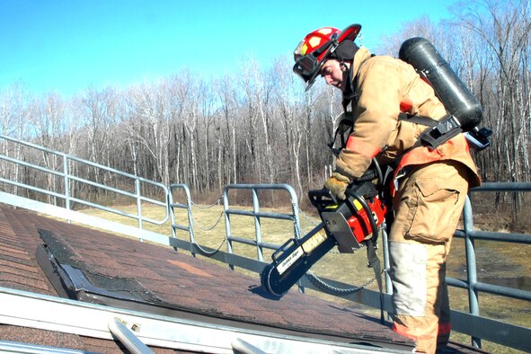 YOUNGSTOWN AIR RESERVE STATION - Mr. Joe Davies, a DOD civilian Fire Fighter for the 910th Airlift Wing here, simulates cutting a hole in the roof of the base fire training facility using a chain saw with a belt guard on it.  Mr. Davies participated in a structure exercise here March 7. (U.S. Air Force Photo by Tech. Sgt. Ken Sloat)