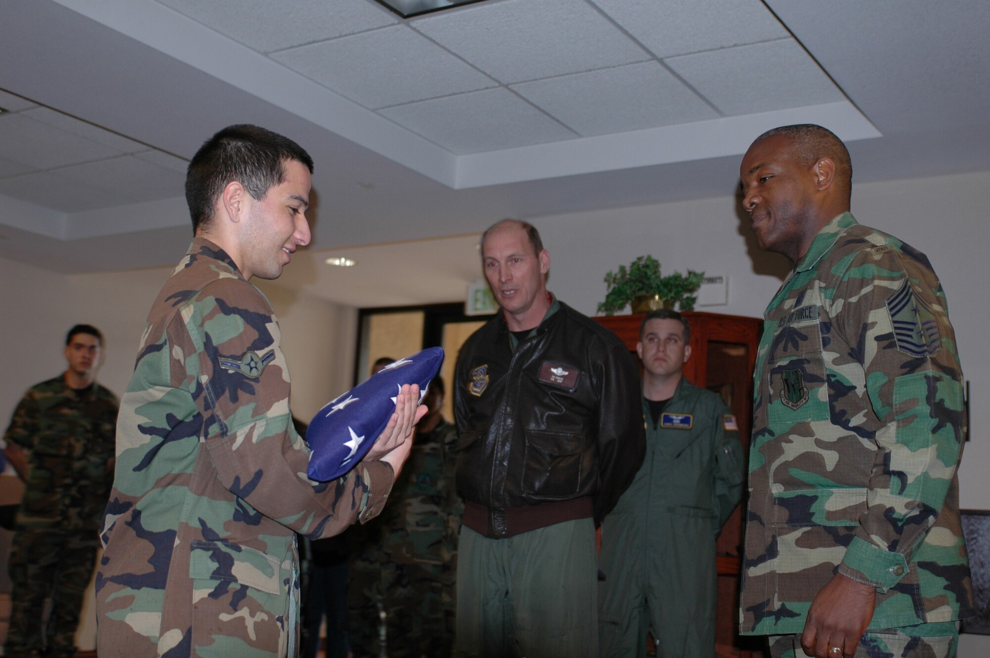 Airman Salvador Gutierrez [left], 60th Aerospace Medicine Squadron, presents Chief Master Sgt. Brye McMillon, 60th AMW command chief, with the United States flag while Col. Timothy Zadalis [middle], 60th AMW acting commander,  attends. The flag was given by the First Term Airmen Center to mark Chief McMillon’s last retreat at Travis before reporting as the18th Air Force command chief. (U.S. Air Force photo by Staff Sgt. Matt McGovern)